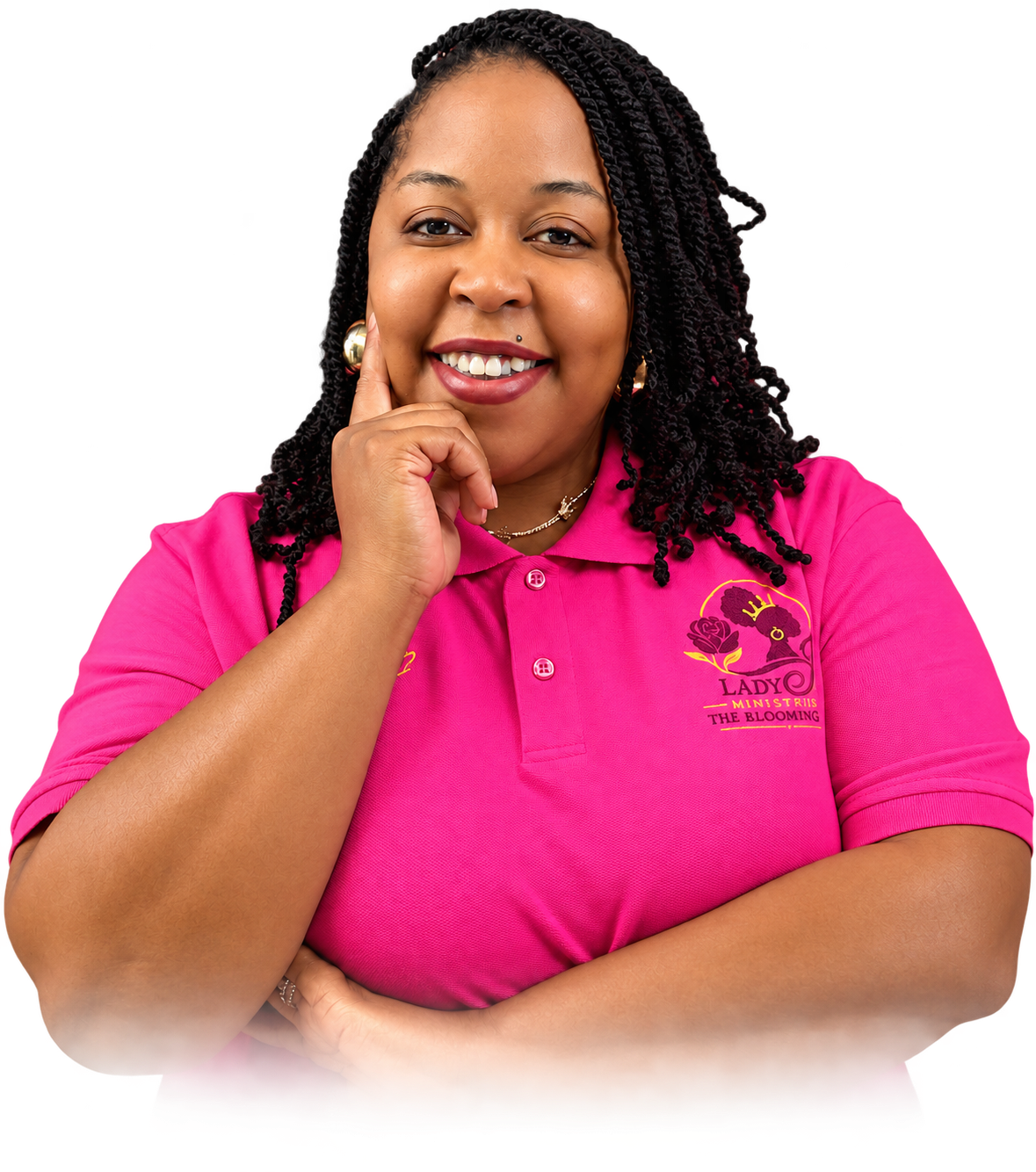 A woman with dark curly hair smiling, wearing a pink polo shirt with a logo that reads 'Lady Ministries The Blooming' and earrings, standing with her hand on her chin against a black background.