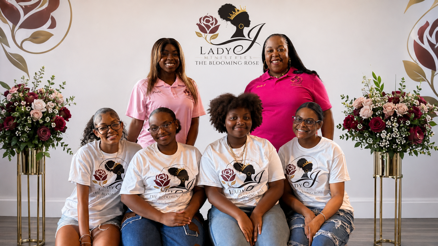 Group photo of five women and girls at Lady J Ministries, The Blooming Rose, event, with floral arrangements and logo featuring a woman's silhouette with a rose and crown.