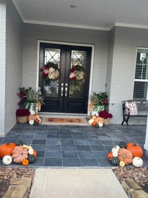 Full porch design - including pumpkins, layered rugs, wreaths, fall picks for planter, basket planter with fake mums & seasonal pillows.