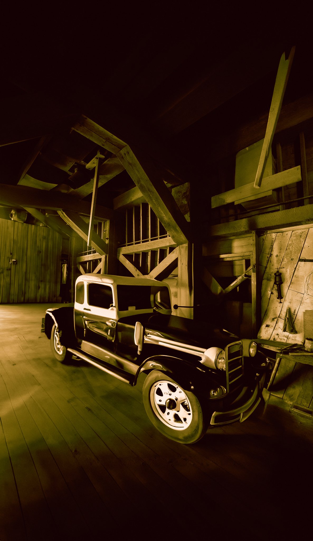 Old vintage-style vehicle resting inside a weathered wooden barn near Bozeman, Montana.