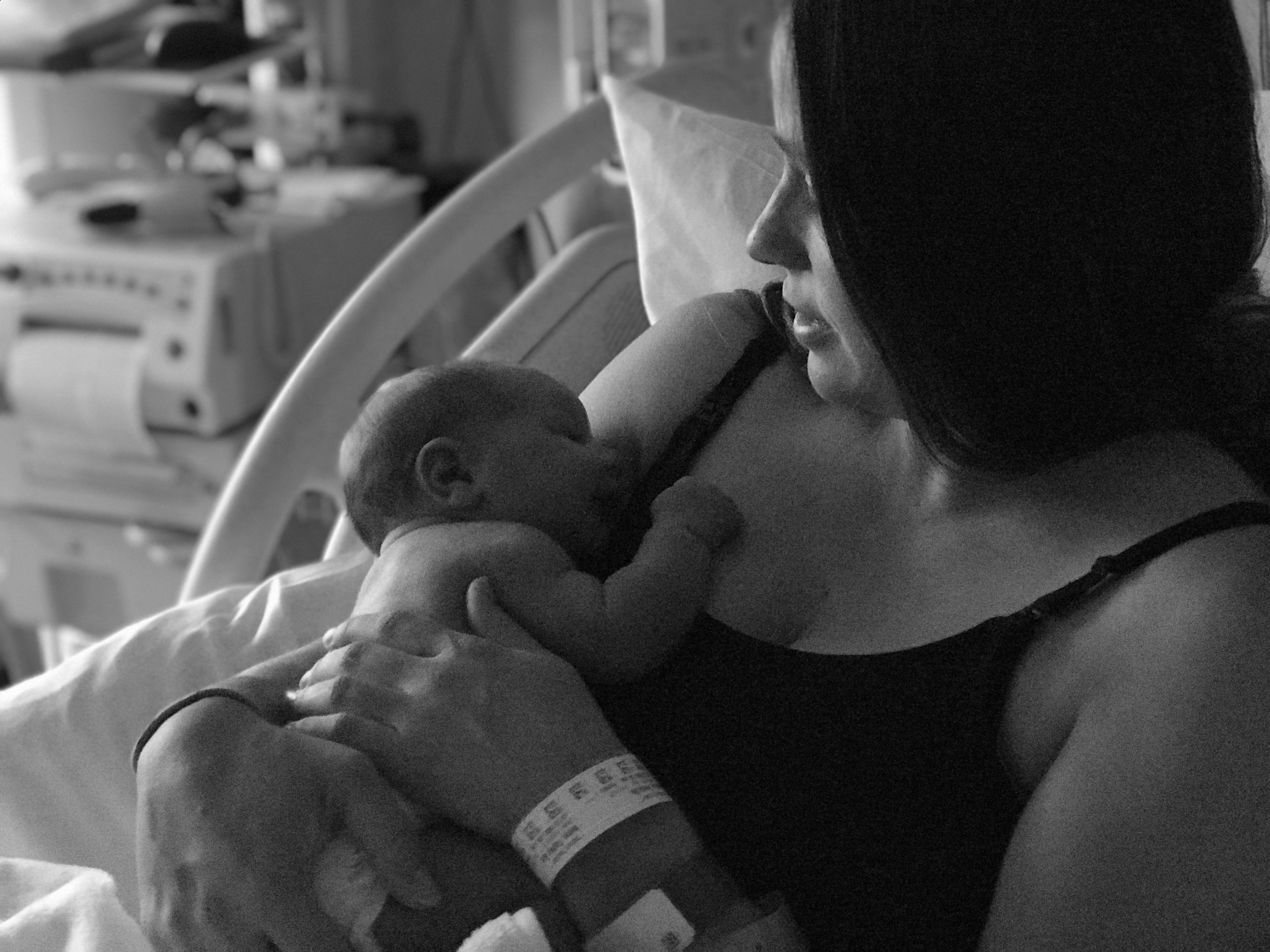B&W photo of mother in hospital bed holding new baby.