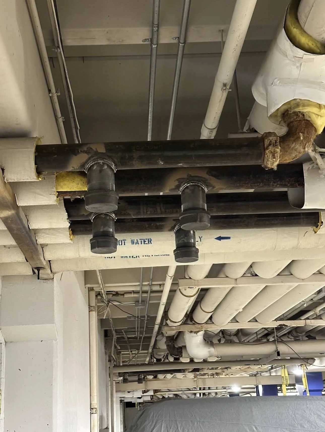 Ceiling pipes and plumbing system in a building basement or utility area.