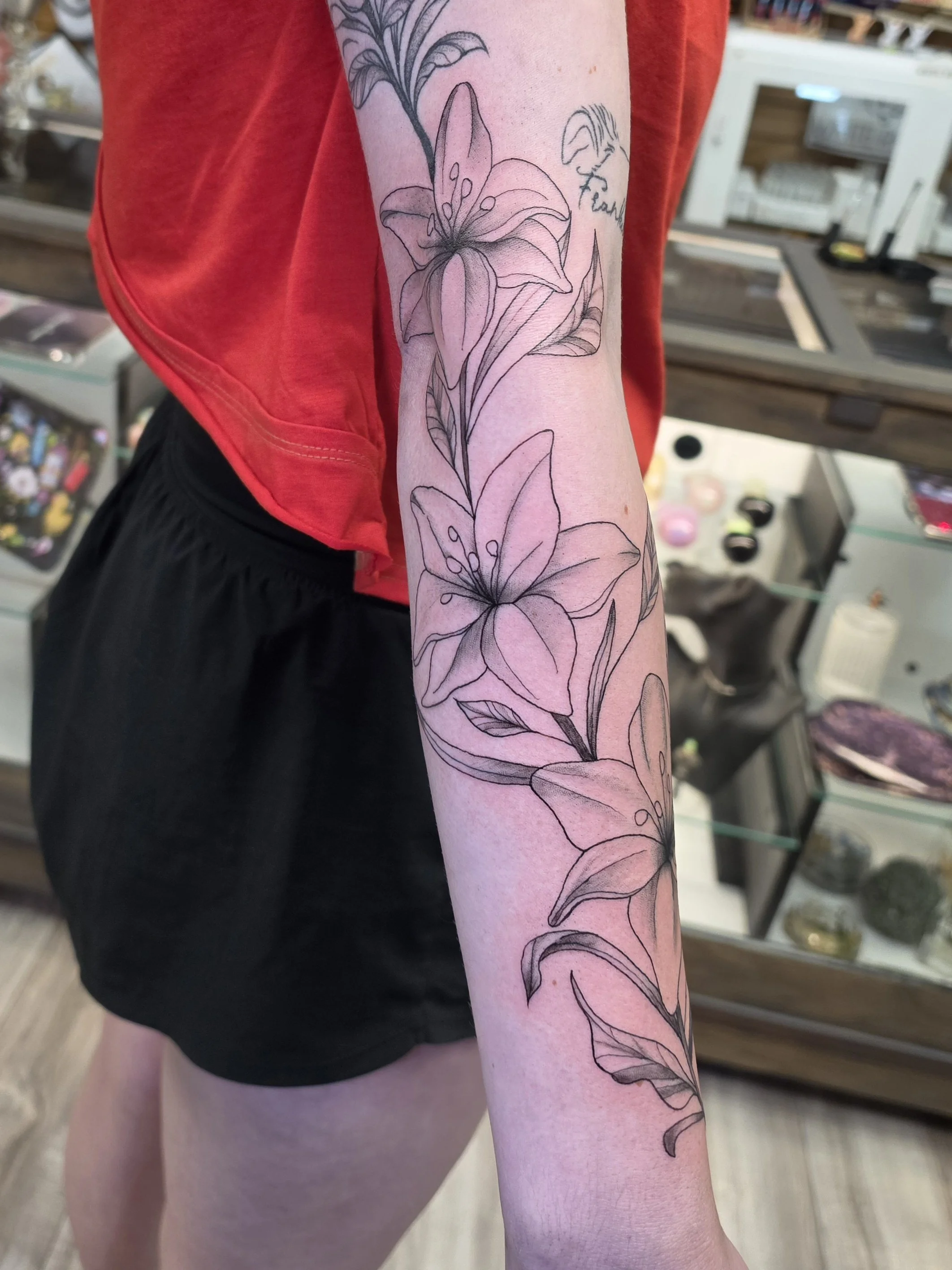 Crybaby Angell, a Colorado tattoo artist tattooed lilies wandering up the forearm