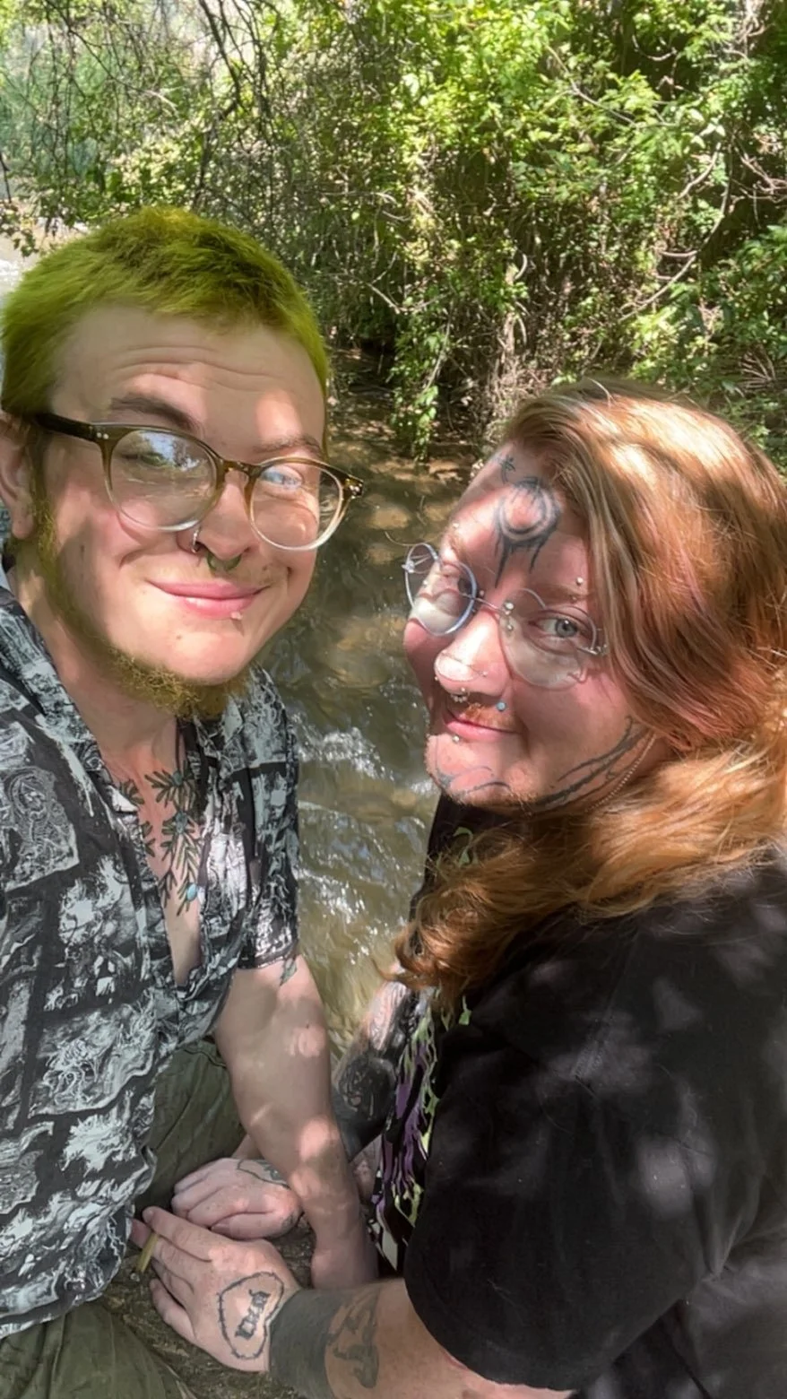 Crybaby Angell, a Colorado tattoo artist posing with his partner Bee at a river.