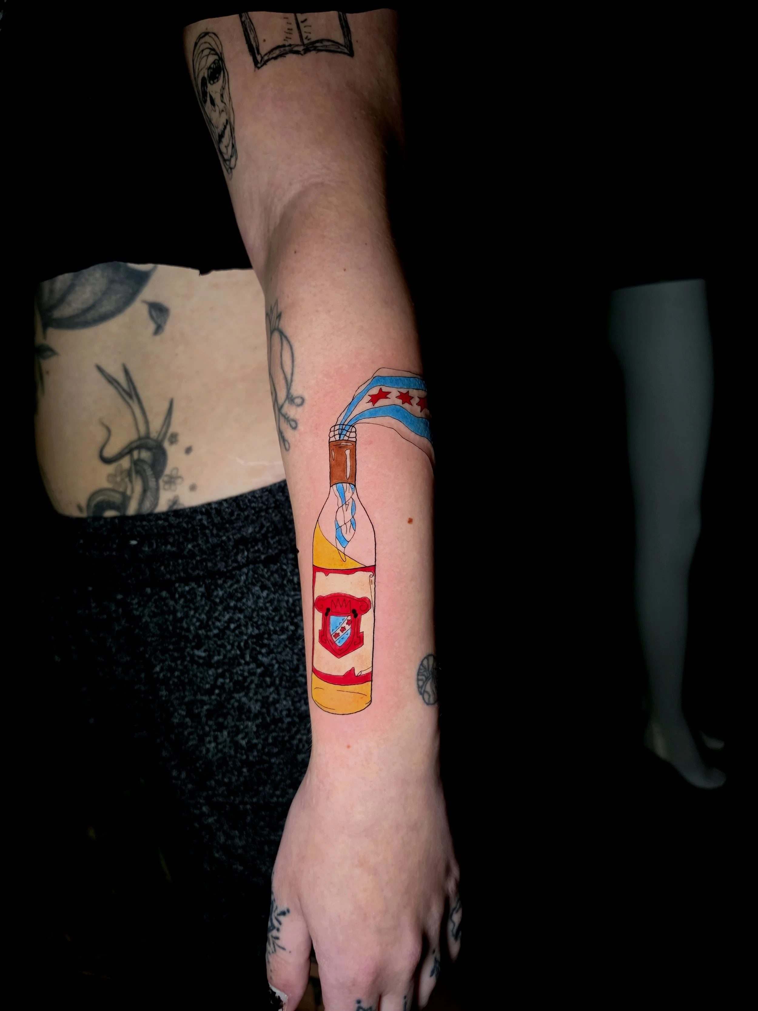 Crybaby Angell, a Colorado tattoo artist tattooed a colorful Malort bottle on the forearm