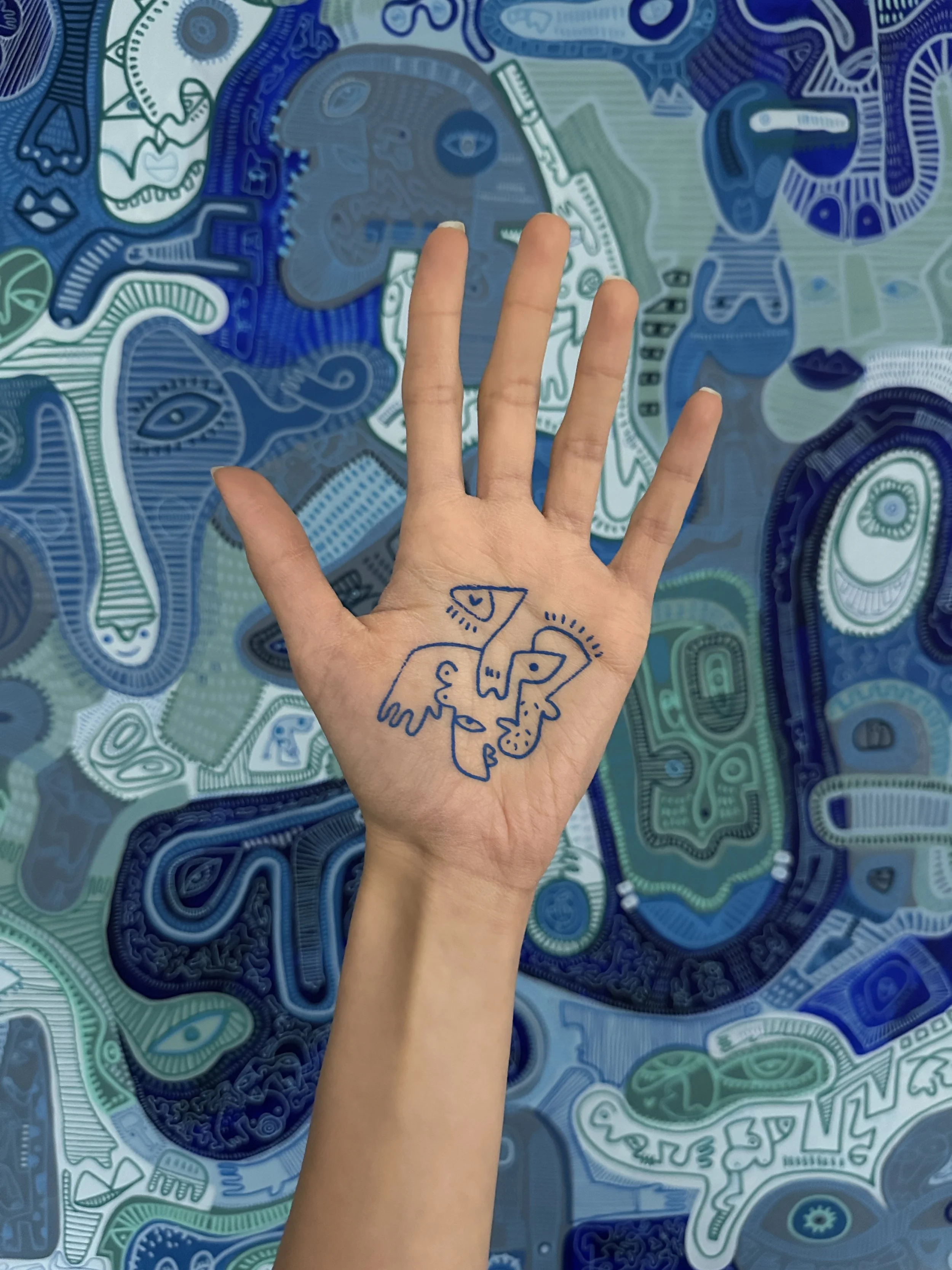 A hand with drawing on the palm, waving over a colorful, abstract, patterned background with various face and animal illustrations in blue and green tones.
