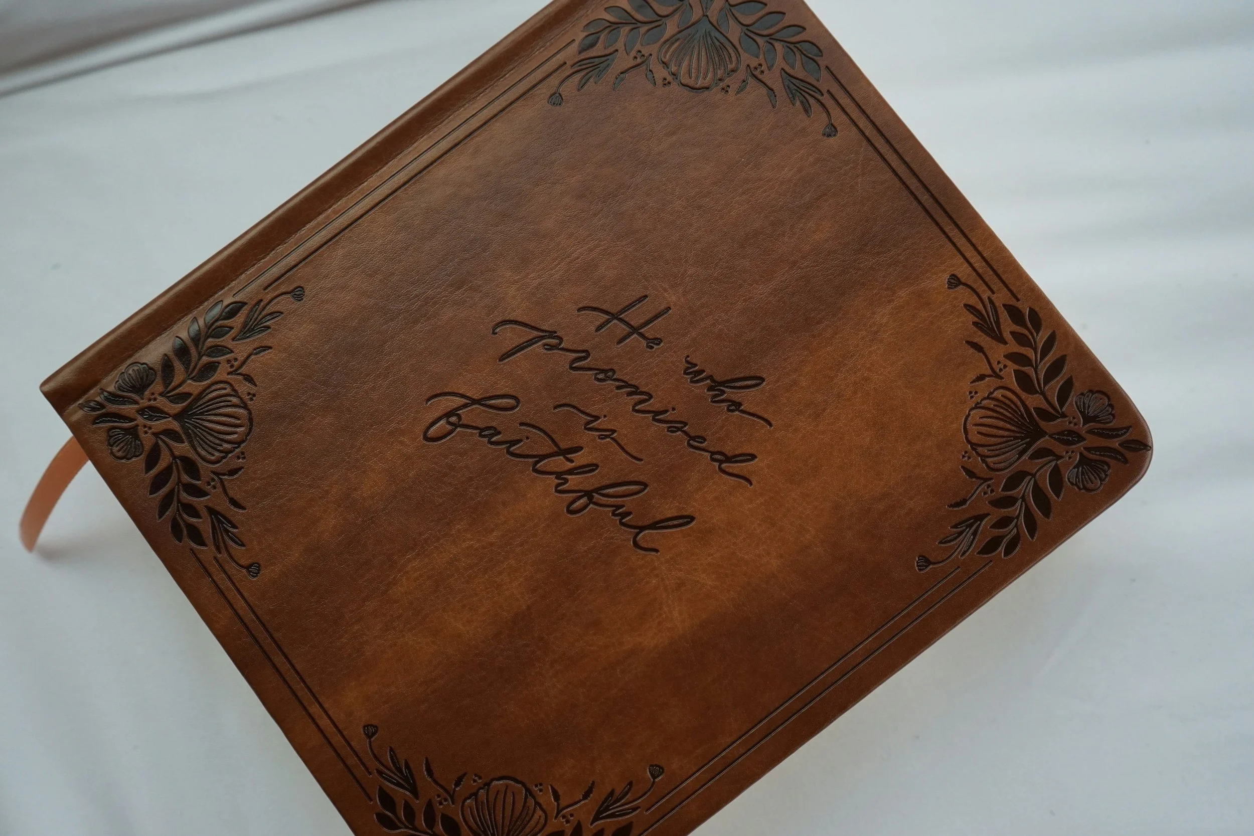 Close-up of a brown leather journal with engraved floral design and the word 'journal' embossed on the cover.