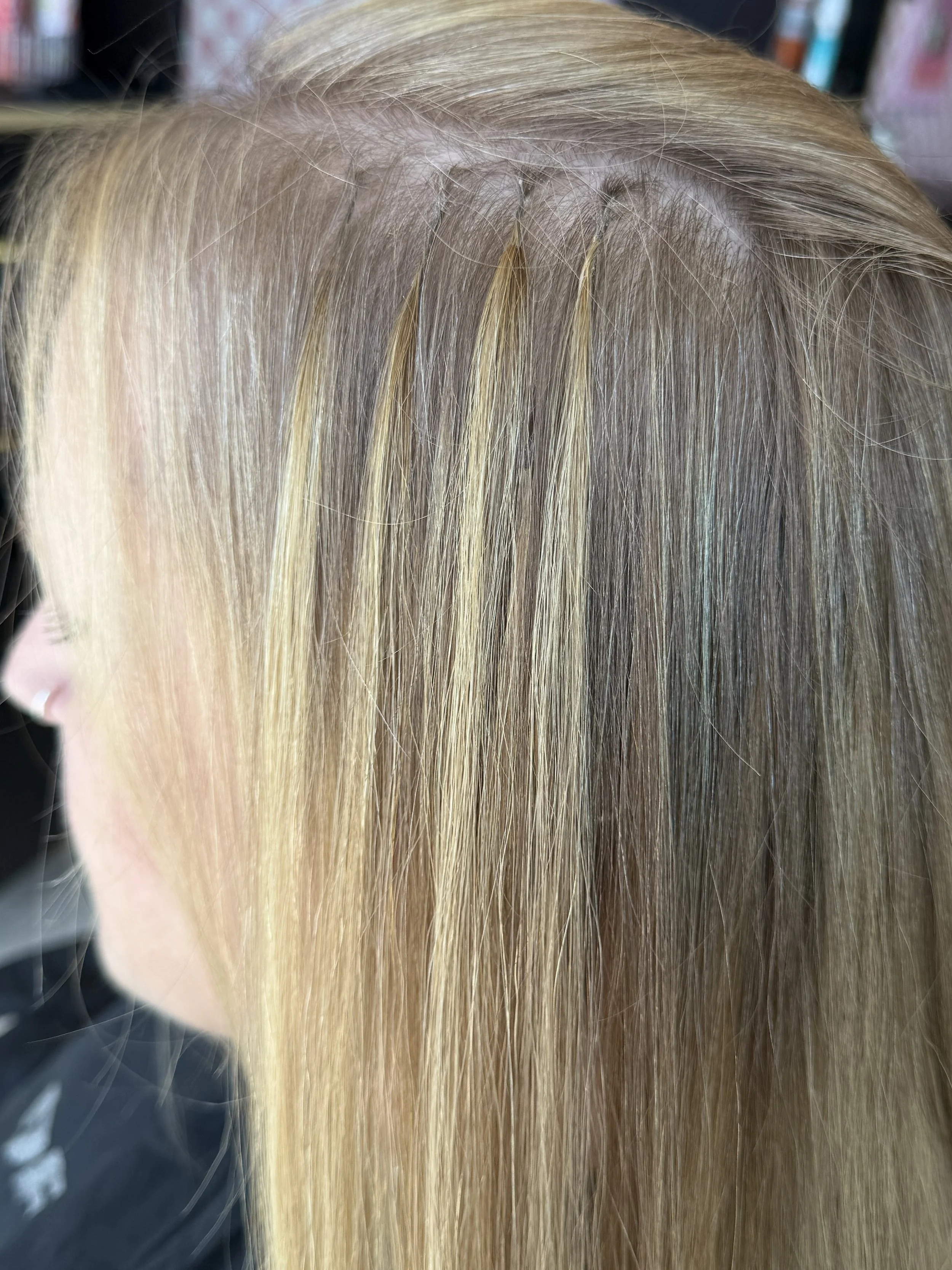 Close-up view of a person's scalp with focusing on healthy, blonde hair falling over the forehead.