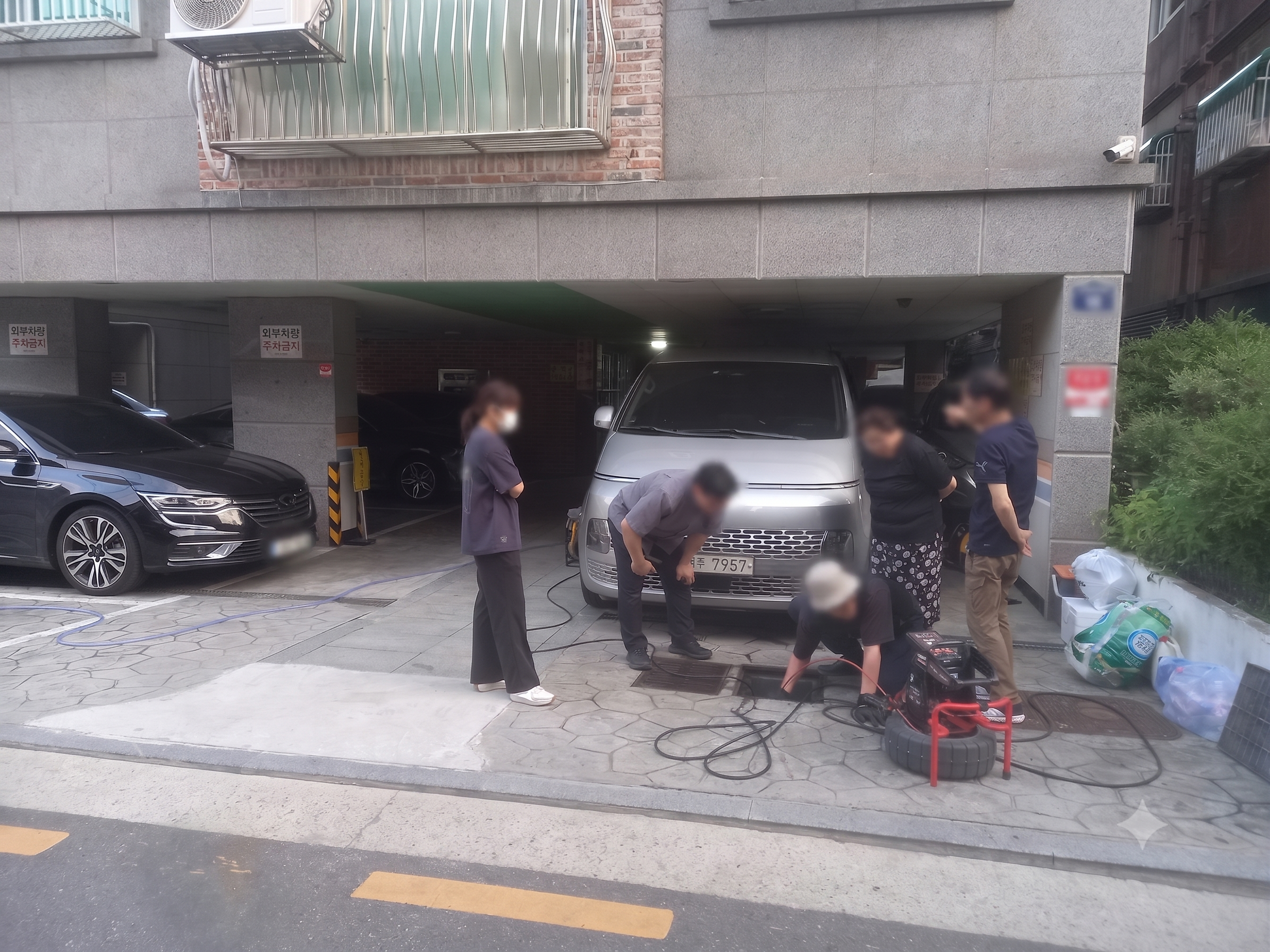 지하 주차장 입구에서 사람들이 전기 장비를 사용하여 작업하는 모습.