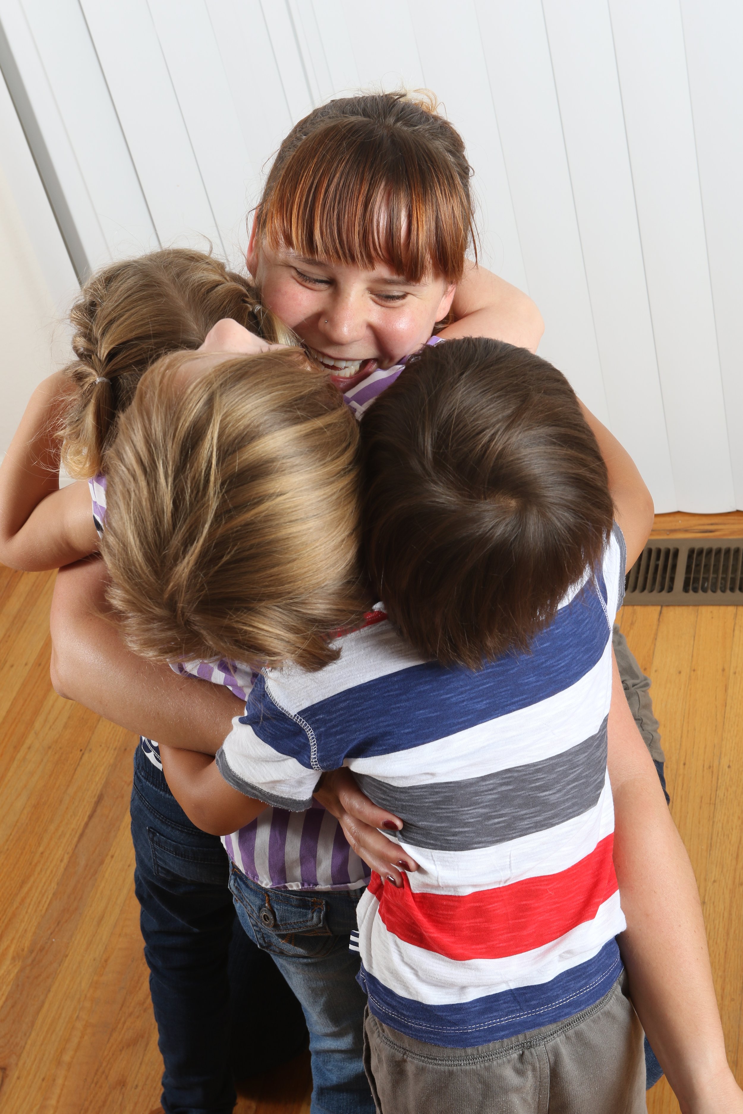 Robin Imholte, the Messy Play Lady, hugging three children.