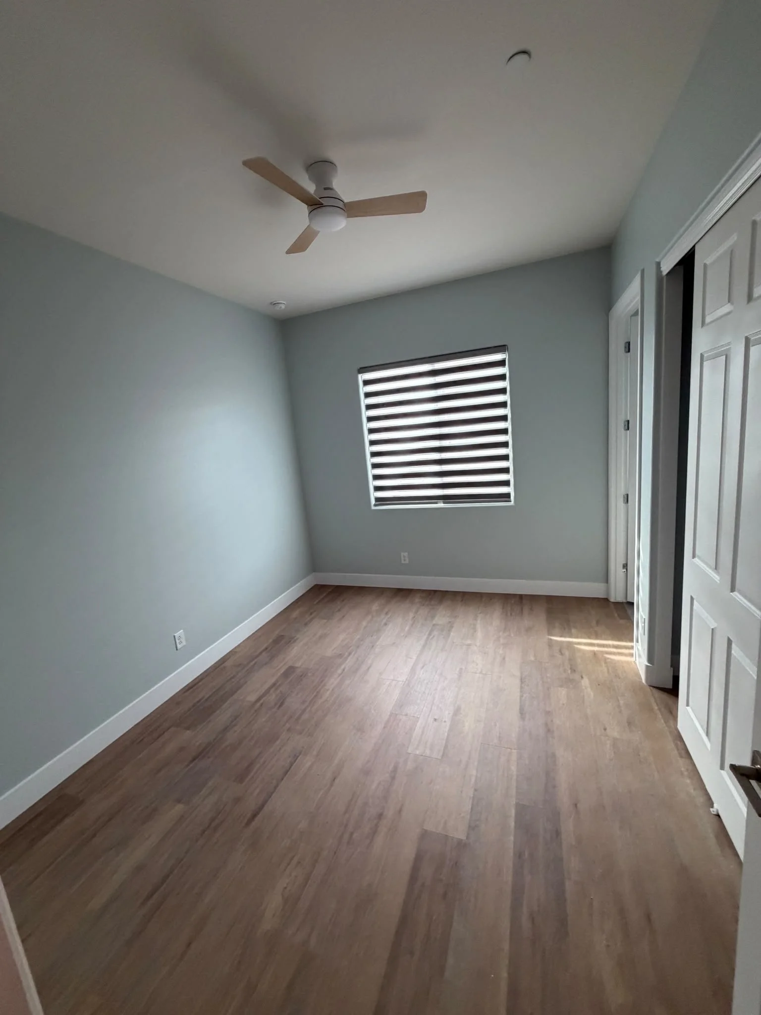 Bedroom remodel with wooden flooring and painted blue walls in Phoenix, AZ
