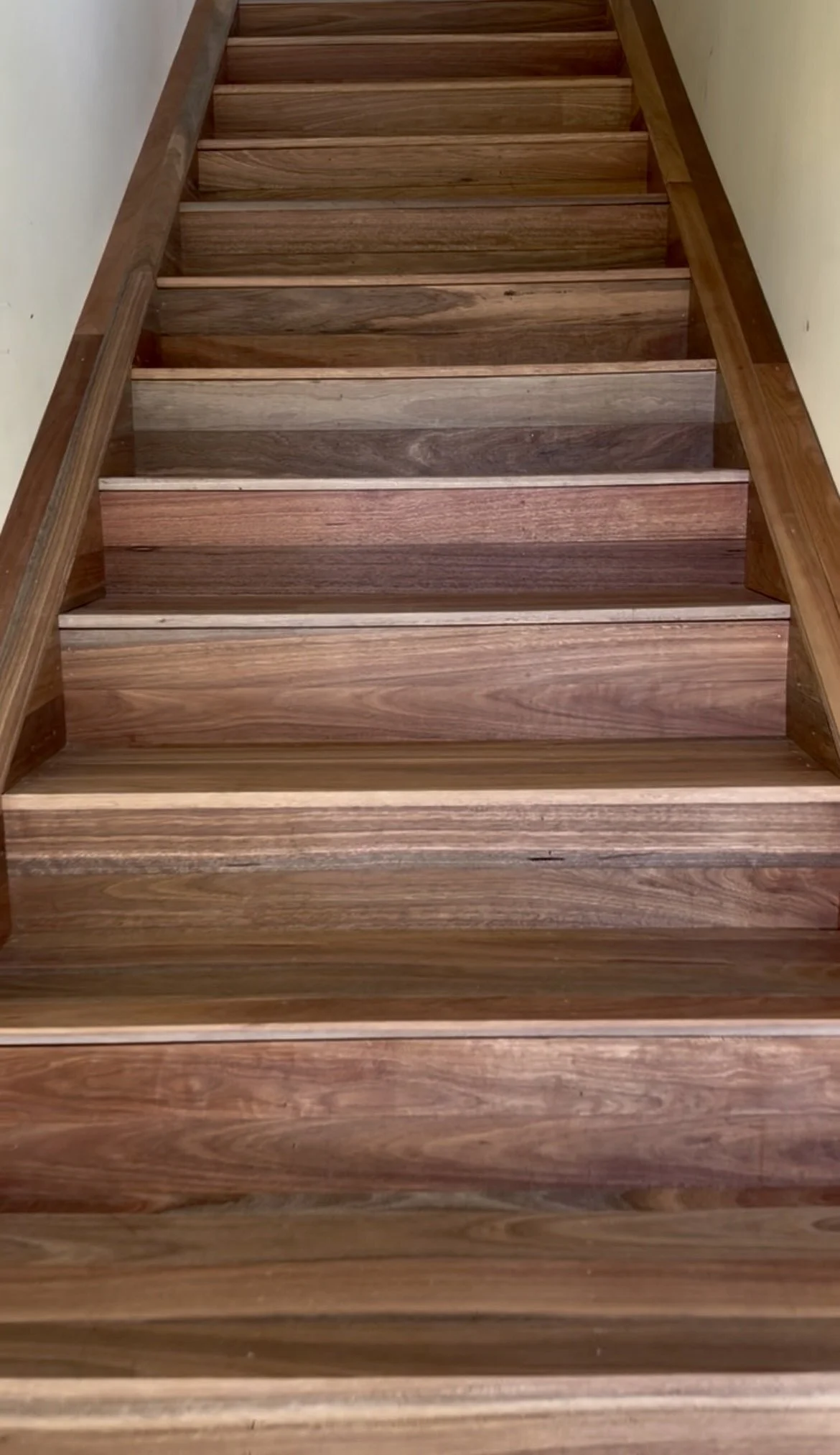 Wooden staircase with natural wood finish, viewed from top to bottom.