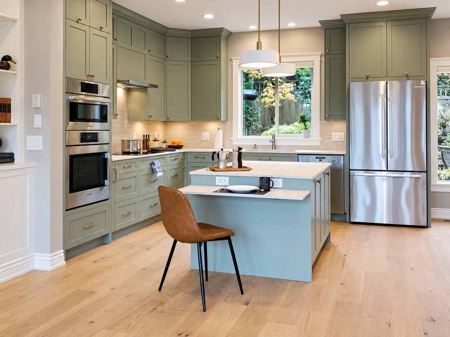 Arcadia kitchen with sage cabinetry, a blue island, brass hardware and a leather counter chair.
