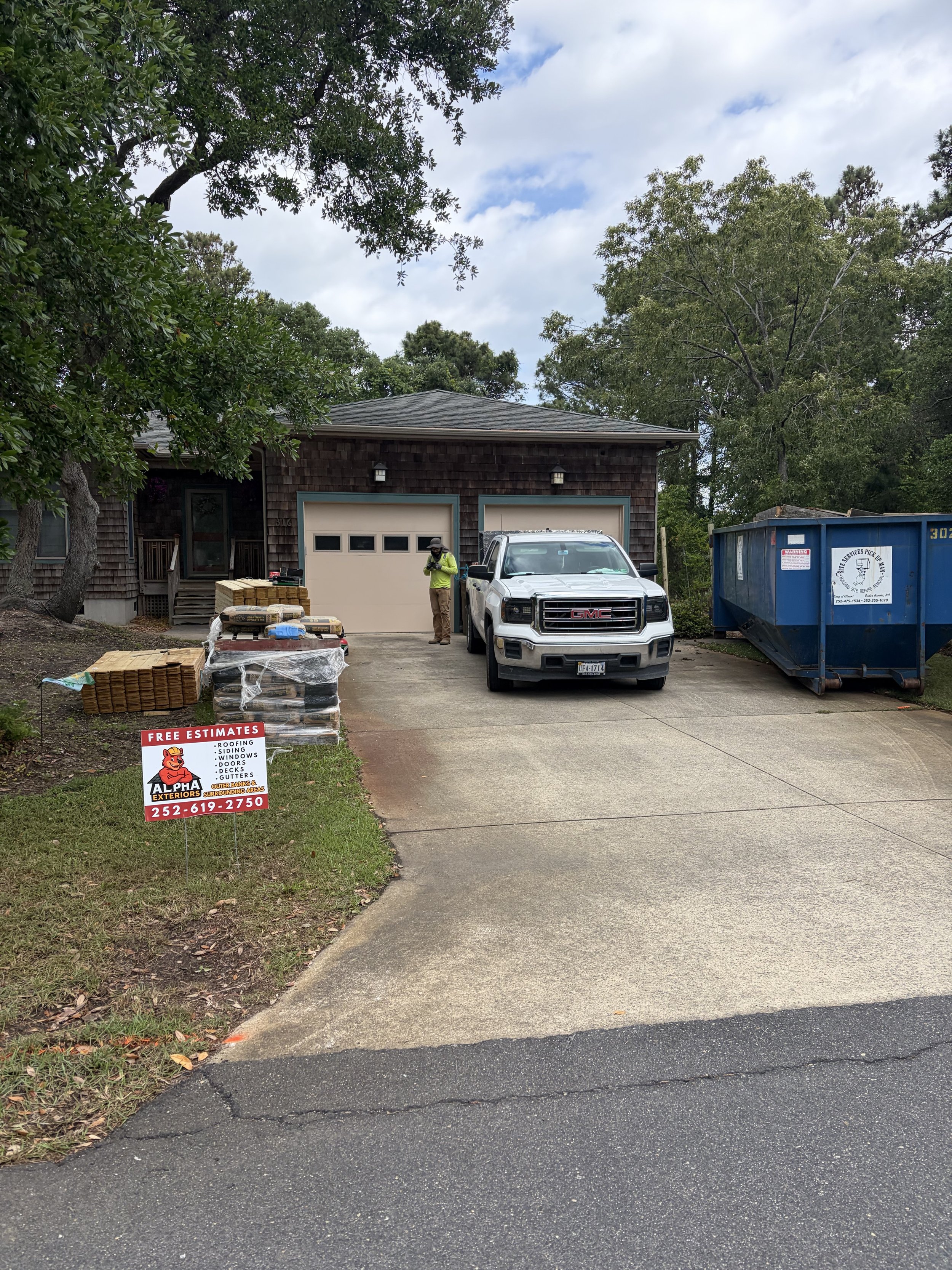 Alpha Exteriors roofing project with materials, work truck, and company sign in the Outer Banks.
