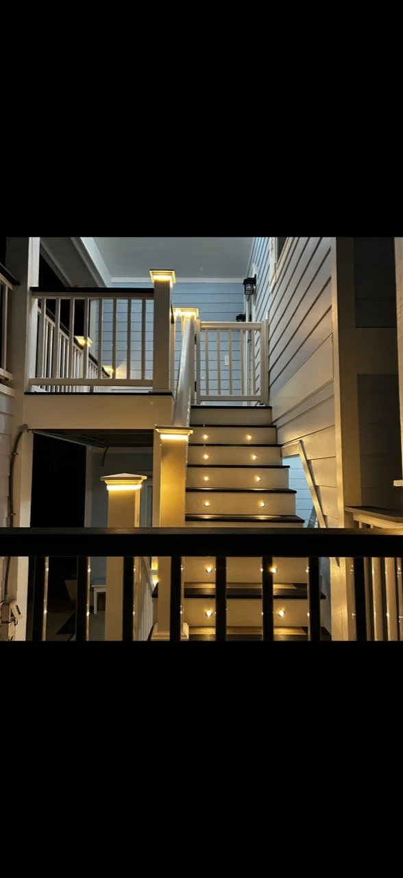 Completed deck stairs with warm stair lights and illuminated post caps by Alpha Exteriors.