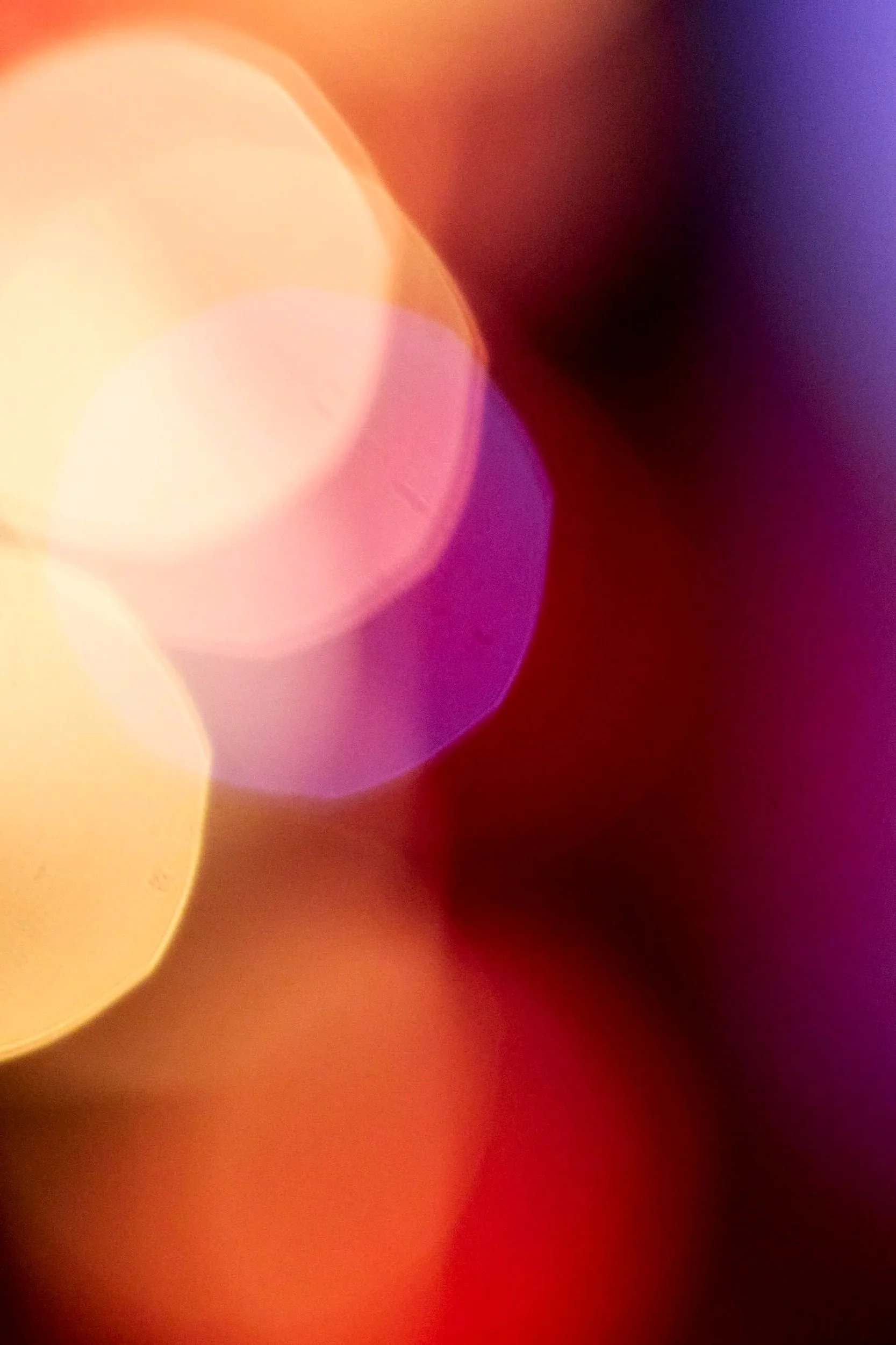 Blurred colorful abstract background with shades of yellow, orange, purple, and red.