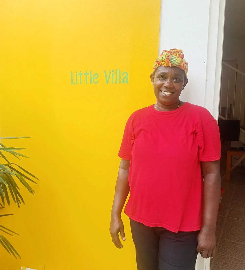 View of Florence the housekeeper standing at the front door of the Little Villa, Mango Garden Cottages, Dominica