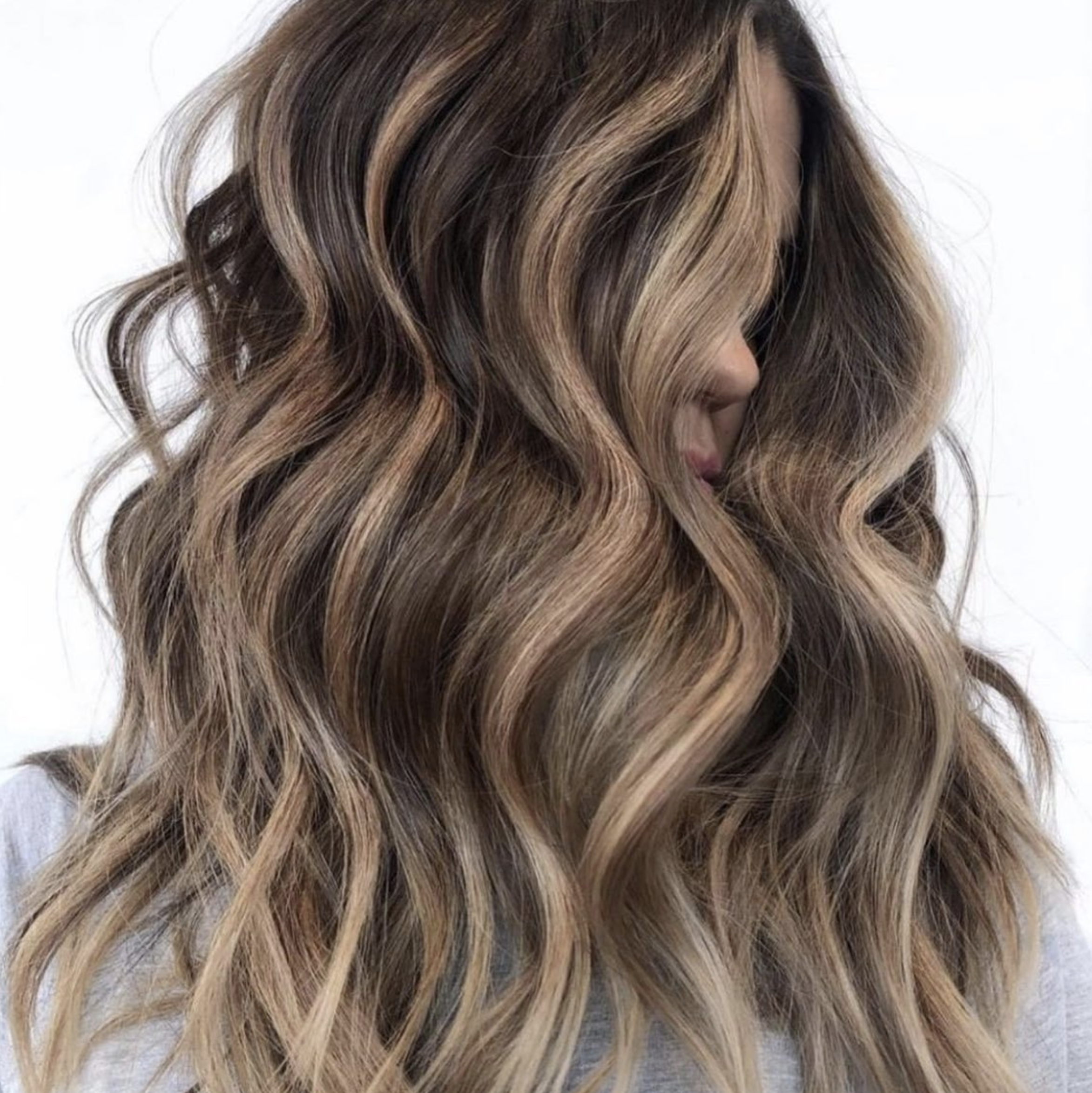 Close-up of a woman's long, wavy hair with blonde highlights.