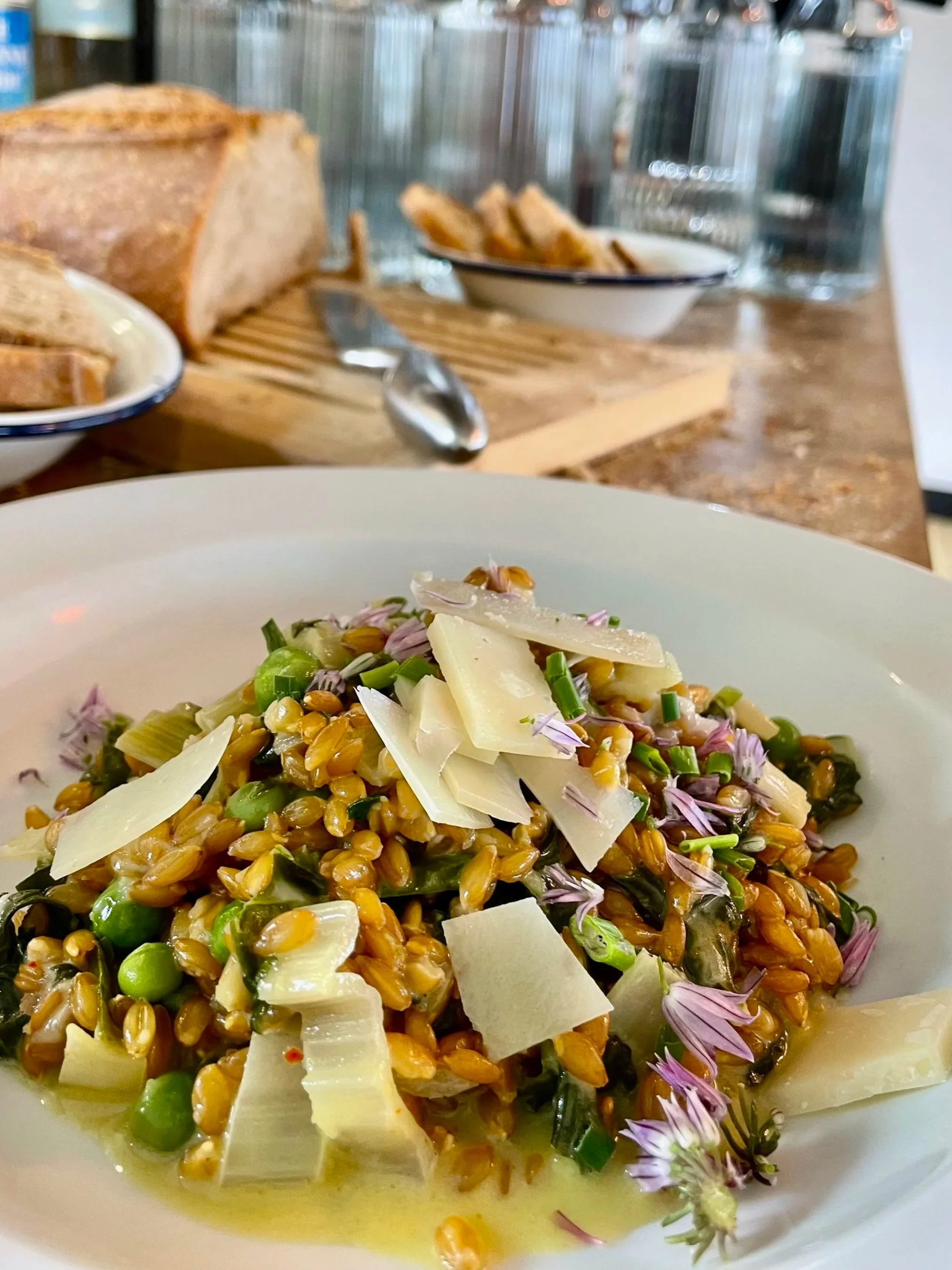 Salade de légumes avec des graines, du fromage en copeaux et des fleurs comestibles dans une assiette blanche.