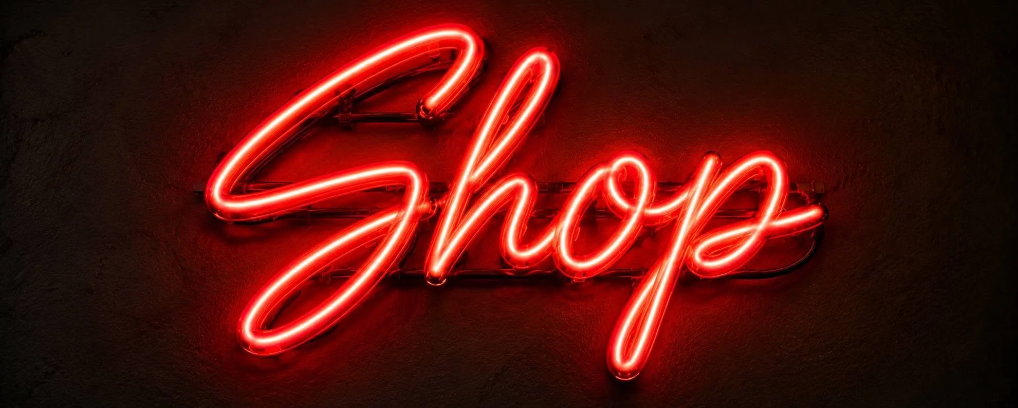 Red neon sign that says 'Shop' mounted on a dark wall.