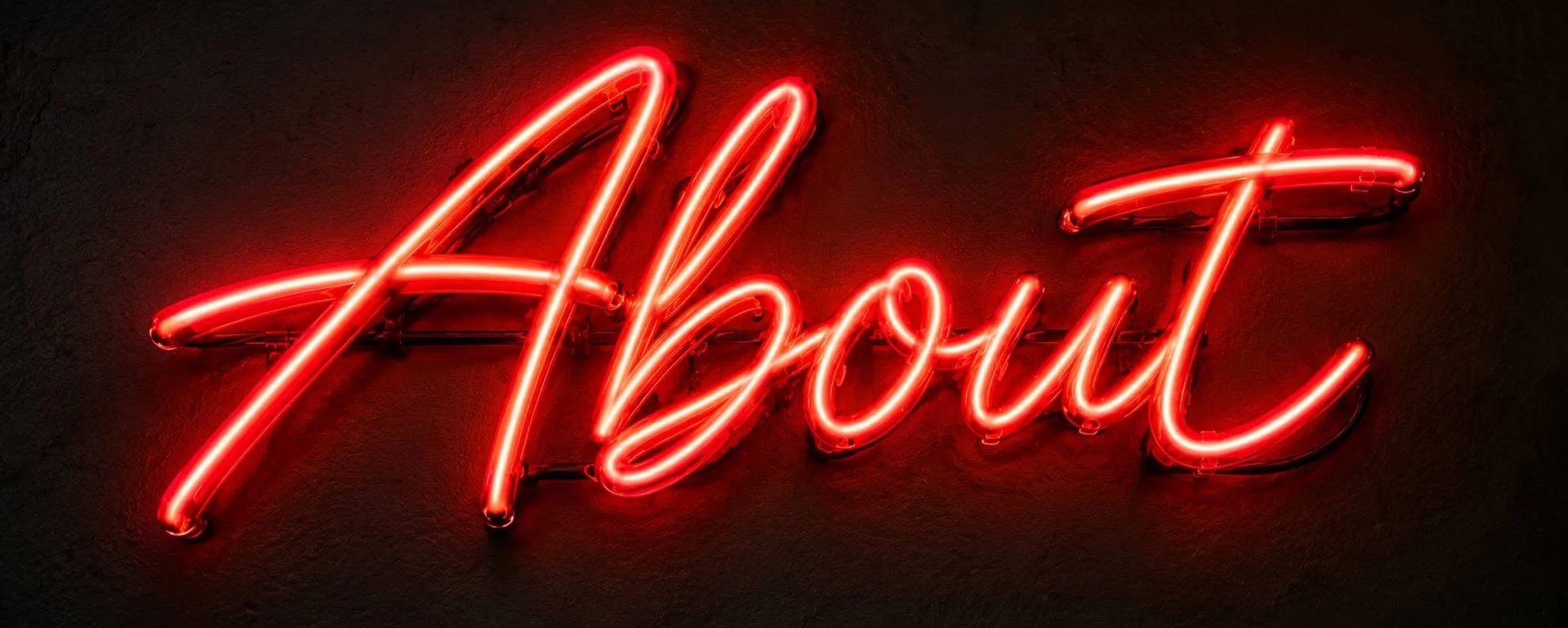 Red neon sign spelling out the word "About" on a dark wall.