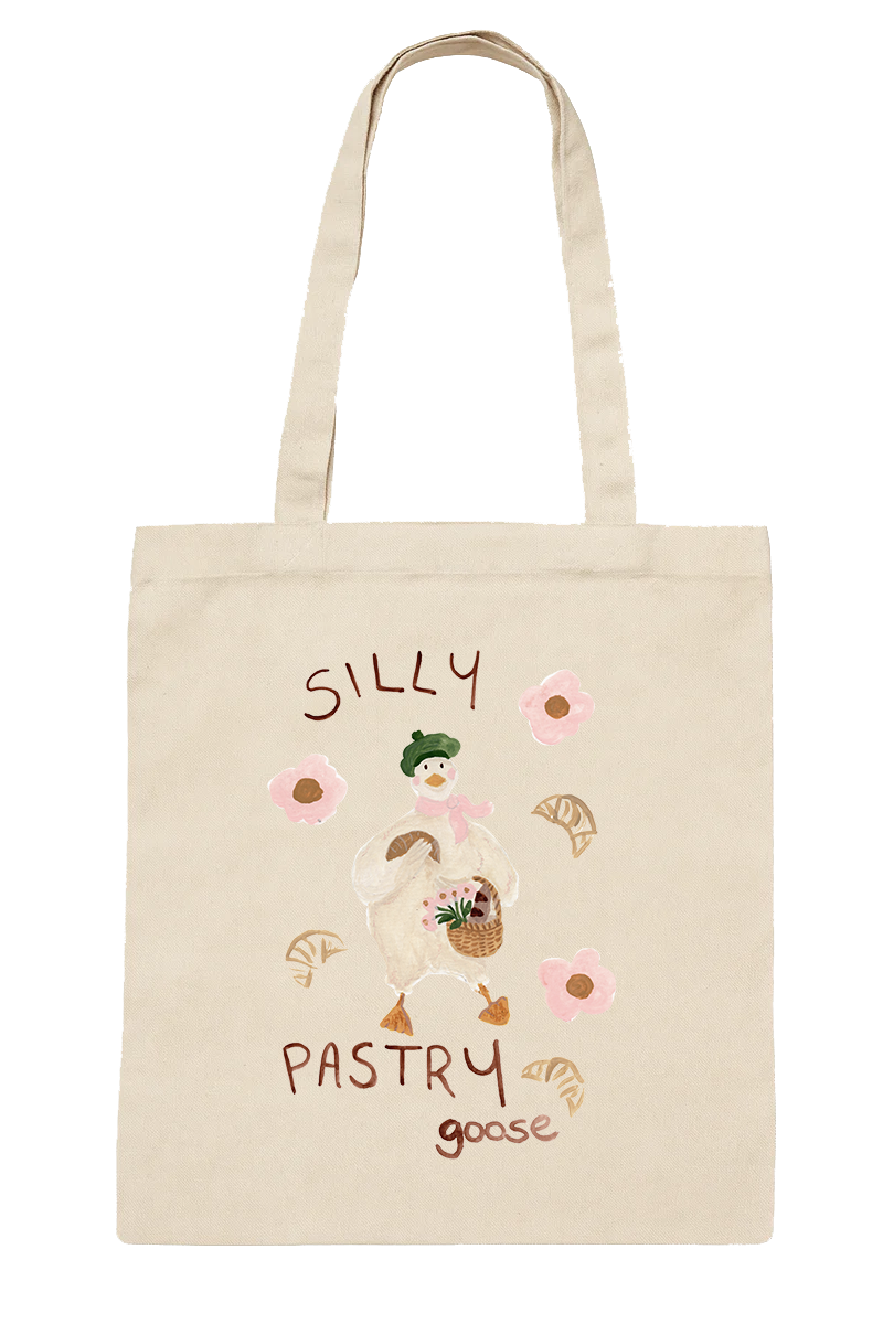 A beige tote bag decorated with a cute illustration of a goose dressed as a baker, holding a basket of pastries, with pink flowers and leaves around it. The words 'Silly Pastry Goose' are written on the bag.