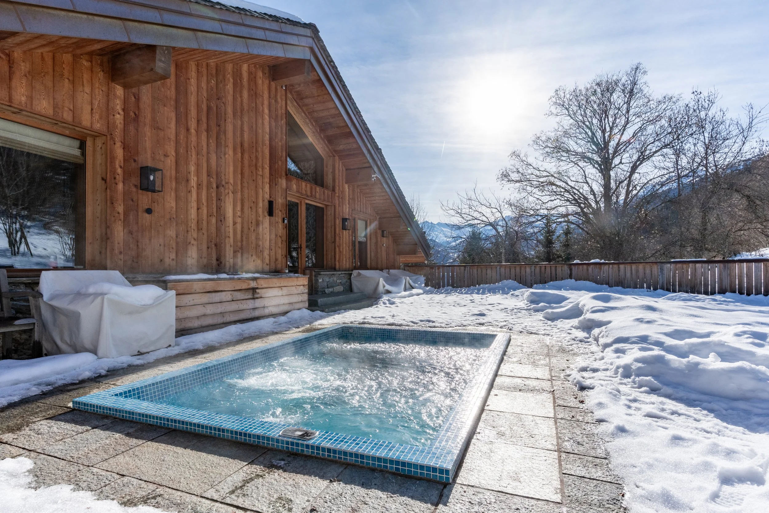 Wood-clad mountain chalet with a steaming blue-tiled pool surrounded by snow
