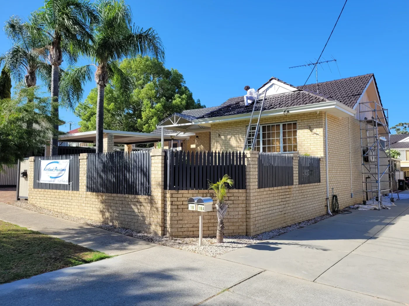 Before repainting: cream house exterior and boundary wall with dark metal fencing.