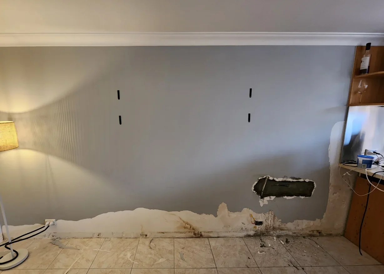 Before restoration: interior wall with damaged plaster, exposed masonry and unfinished lower sections.