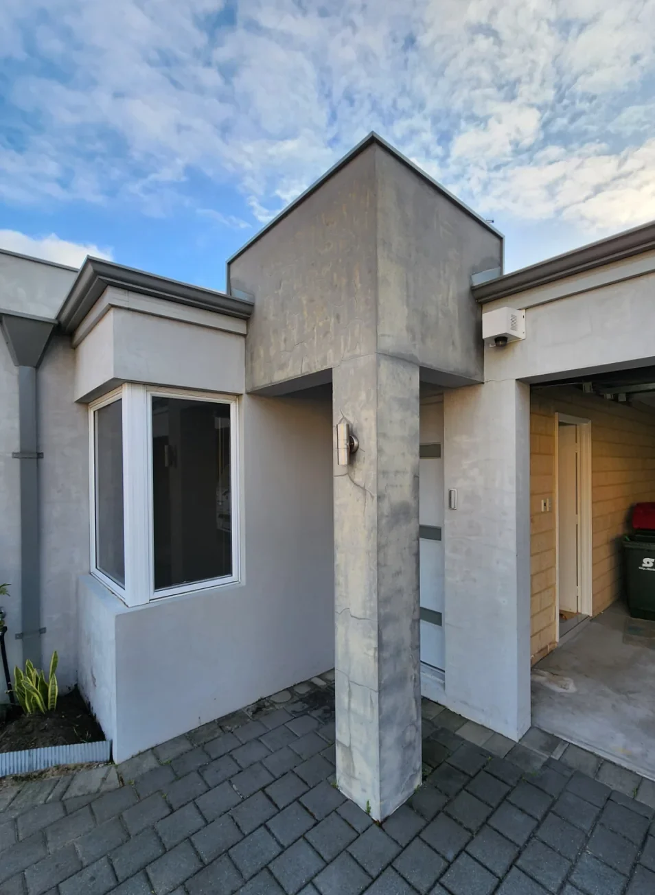 Before repainting: weathered rendered entrance with tall columns beside the front door.