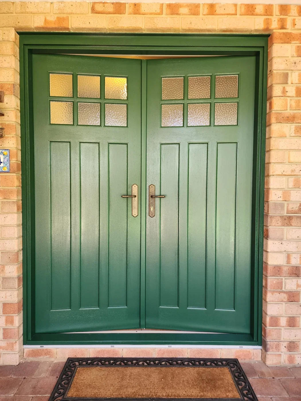 After: A pale timber entrance transformed with a rich green finish across the doors and frame.