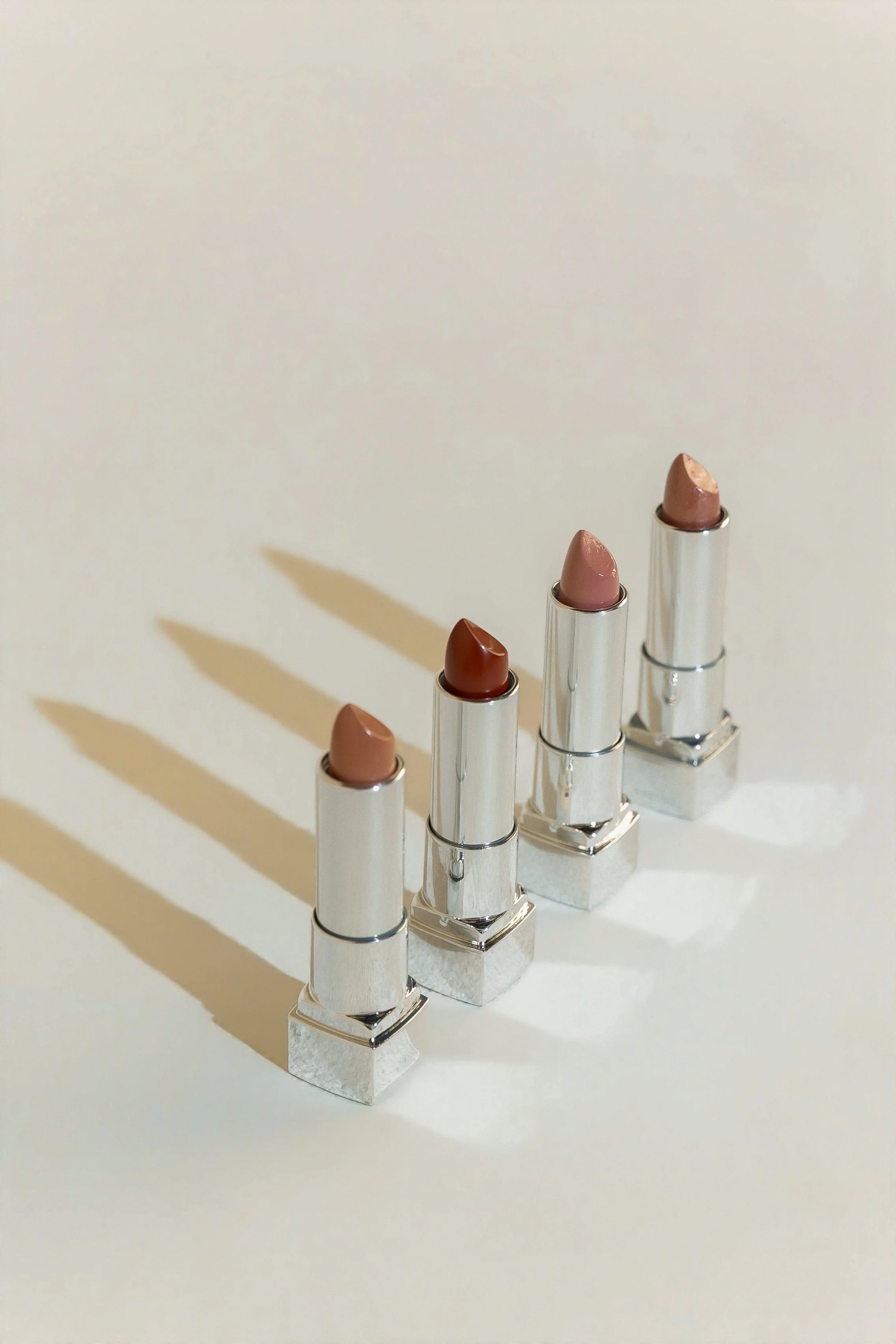 Selection of lipsticks in nude, pink, and red shades arranged for a beauty editorial.