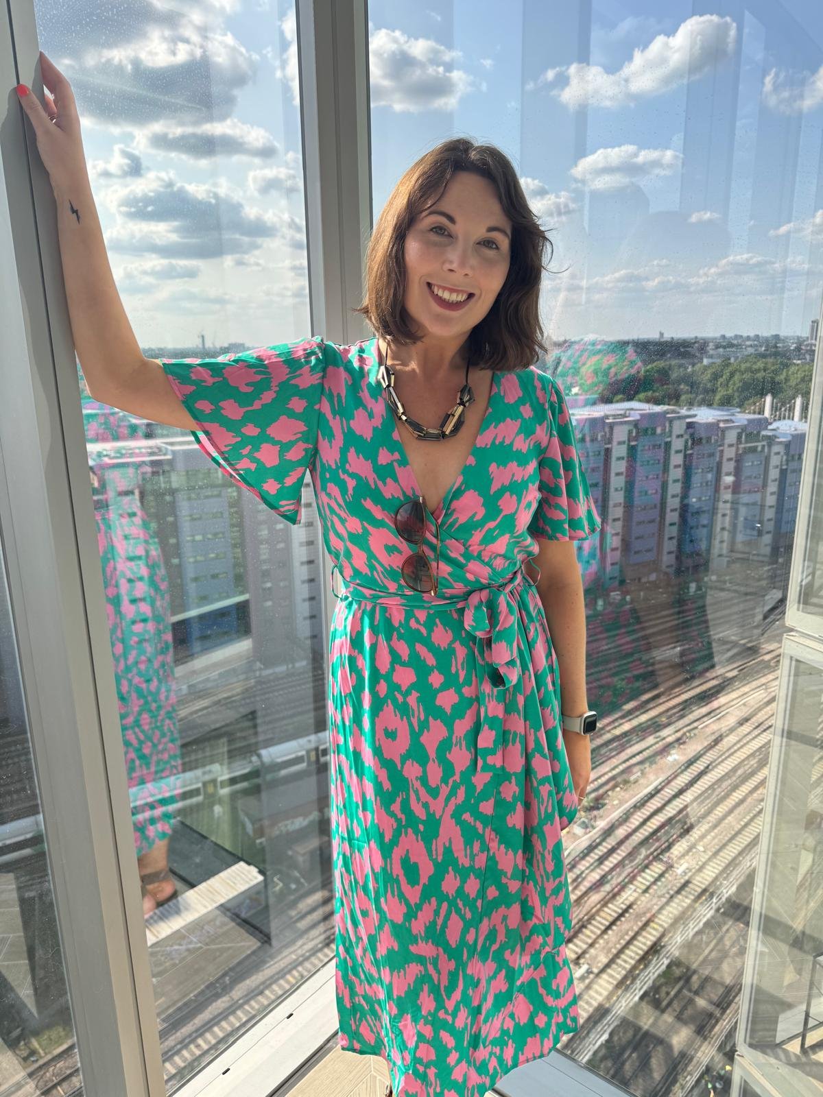 A woman stands with an open, smiling expression