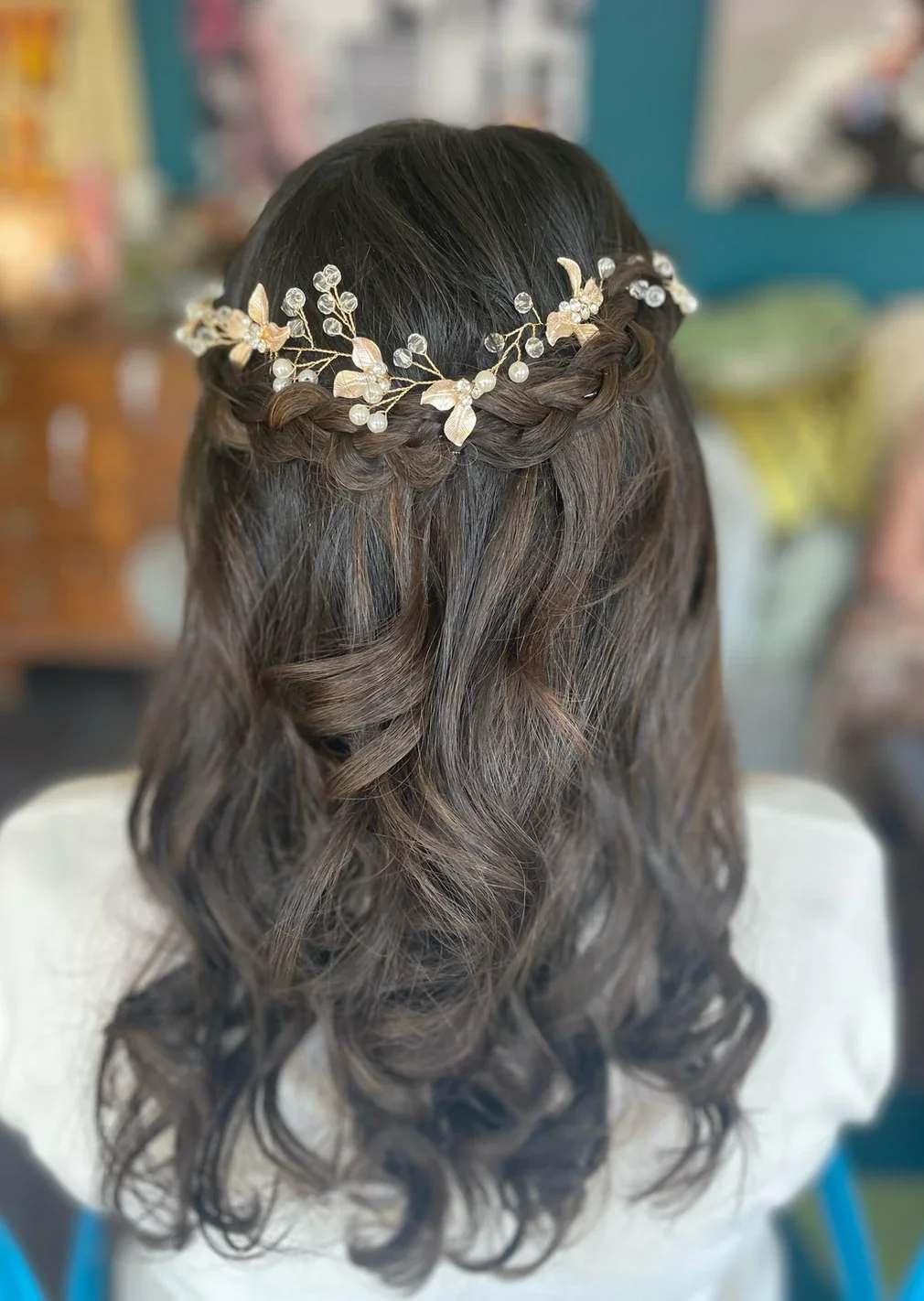Claire Field Bridal Hair and Make up. Back view of a woman with styled wavy hair wearing a delicate gold floral hairpiece with pearls.