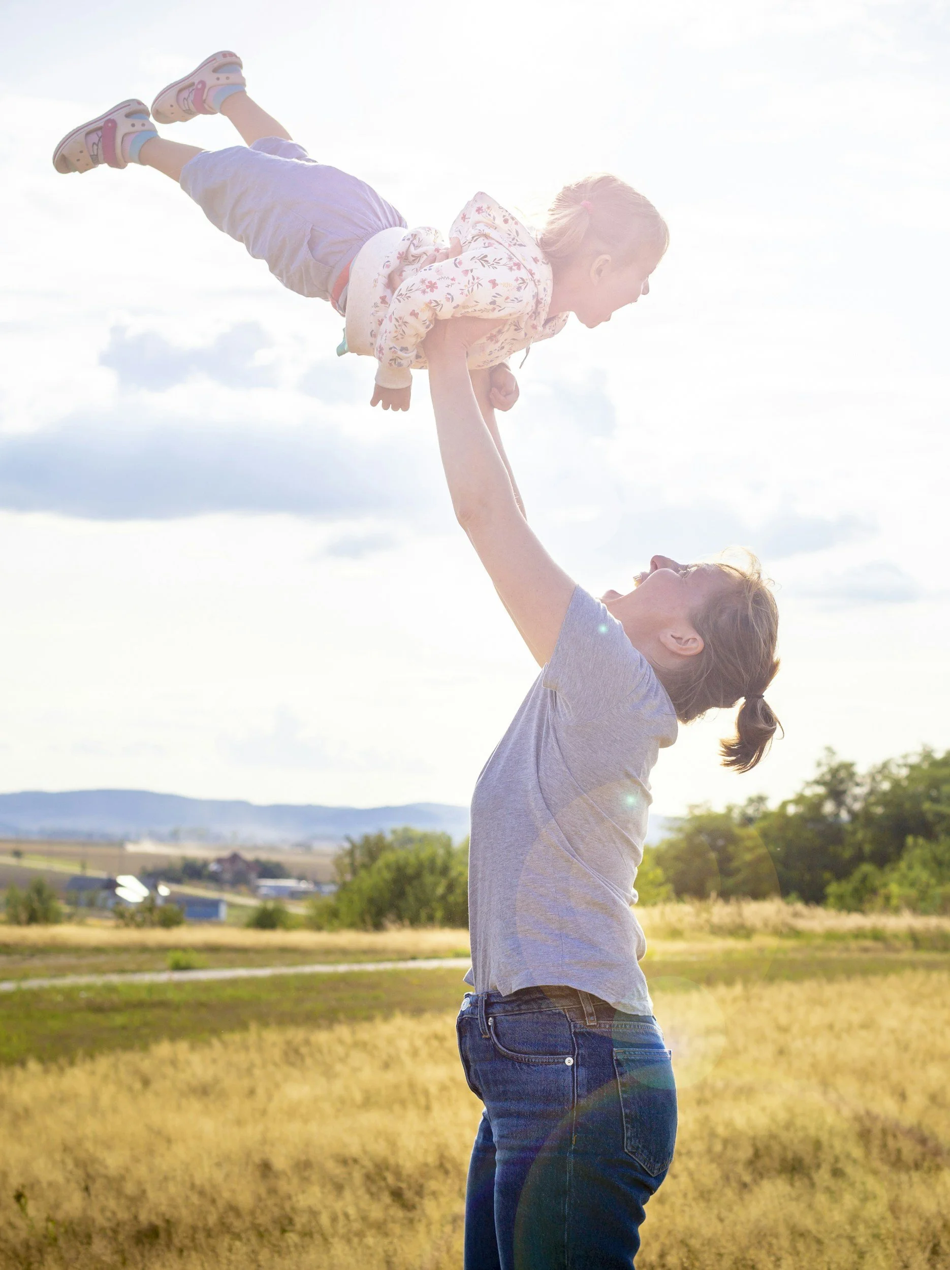 Mother using her core strength to lift her child in the air