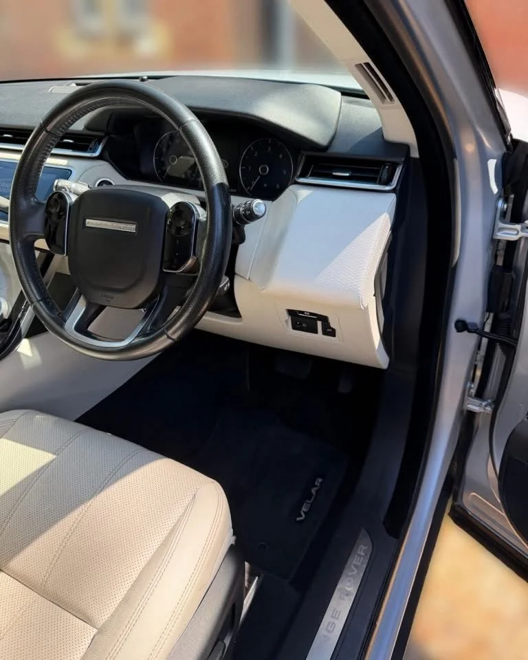 Interior of a Toyota Venza, showing a steering wheel, dashboard, beige seat, and black floor mat.