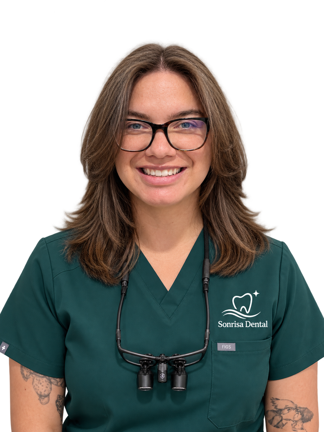 A smiling woman with glasses wearing green dental scrubs with a stethoscope around her neck, standing in front of a neutral background.