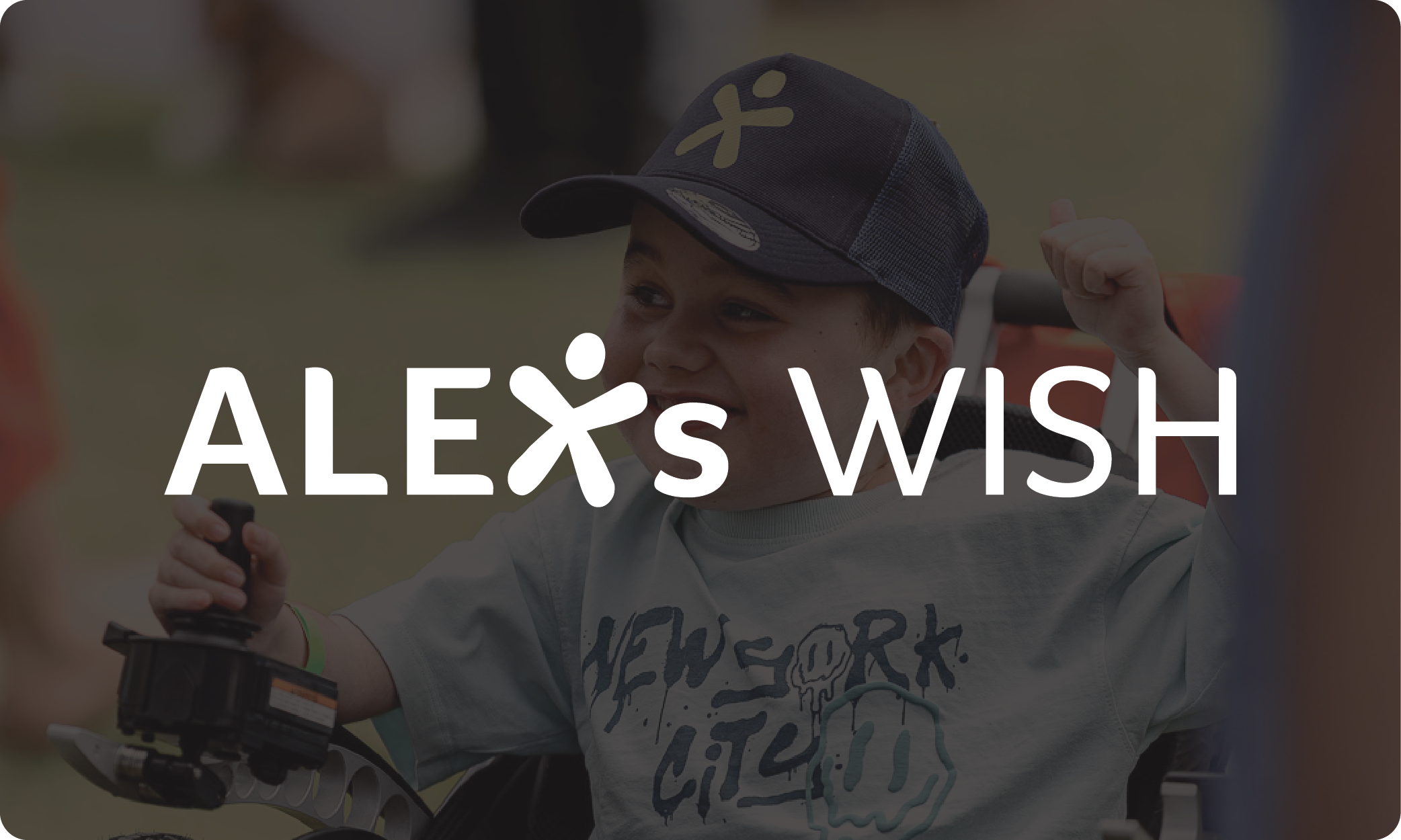 A young boy with Duchenne wears a dark baseball cap with a design and smiles as he sits in his wheelchair. Overlaid text says 'Alex's Wish' in logo form.