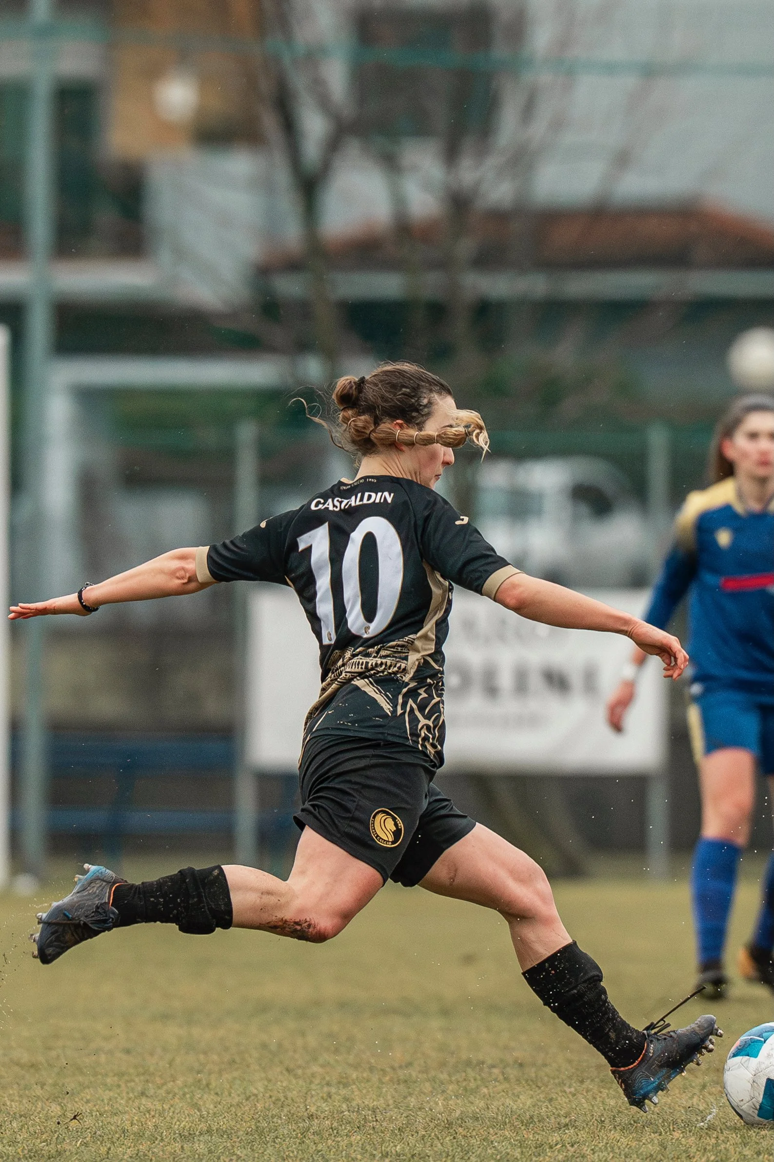 Una giocatrice di calcio in azione, che corre nel campo e sta cercando di calciare il pallone.