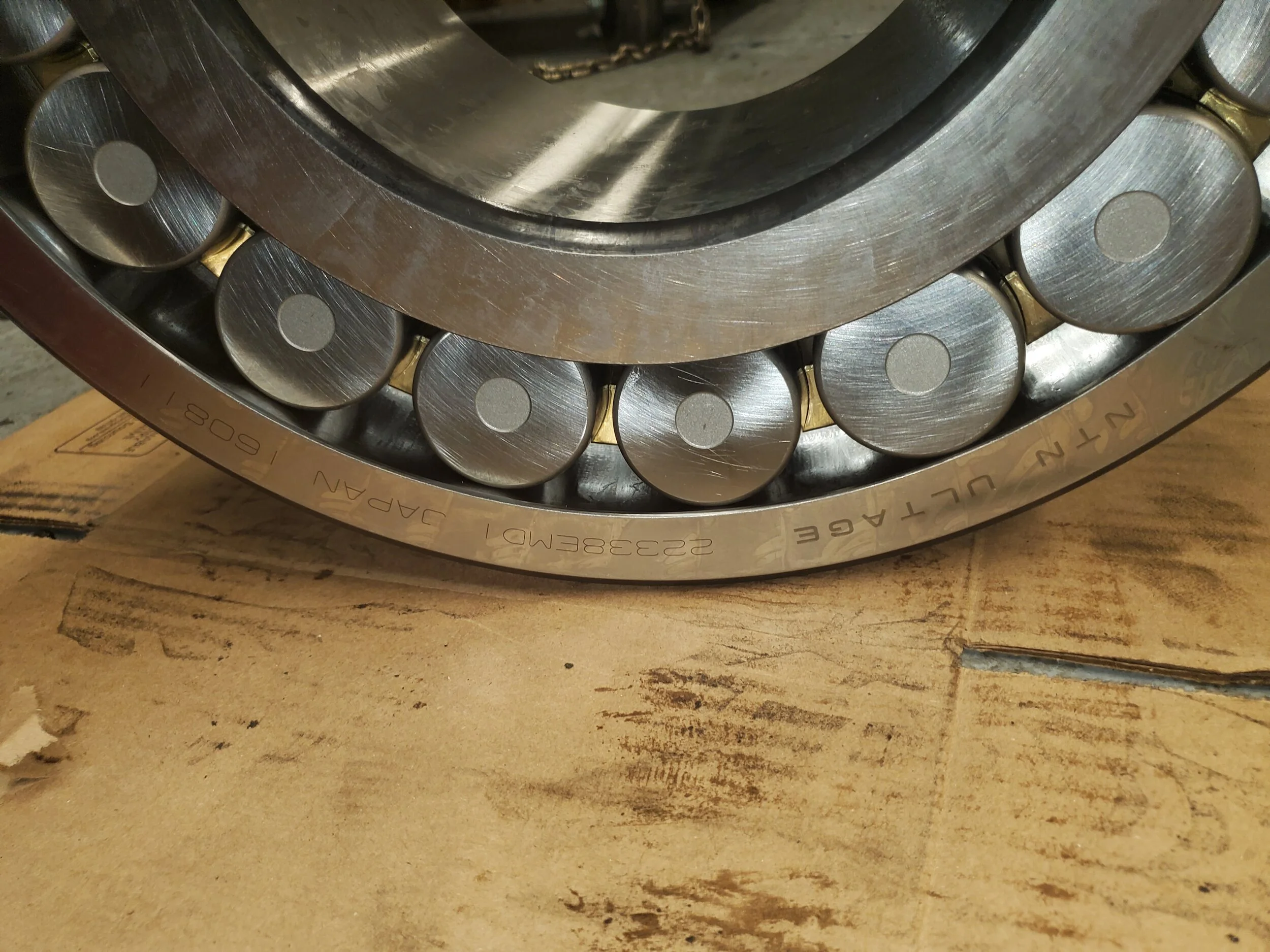 Close-up of a large, circular metal bearing with multiple roller pins, resting on a wooden surface.