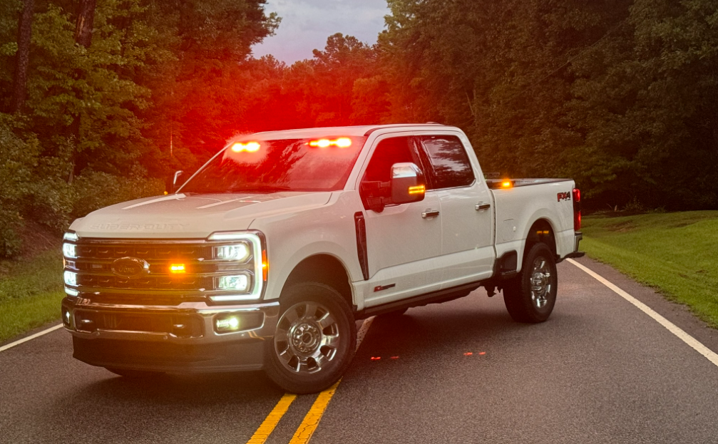 White emergency response pickup truck with warning lights operating on a rural road.