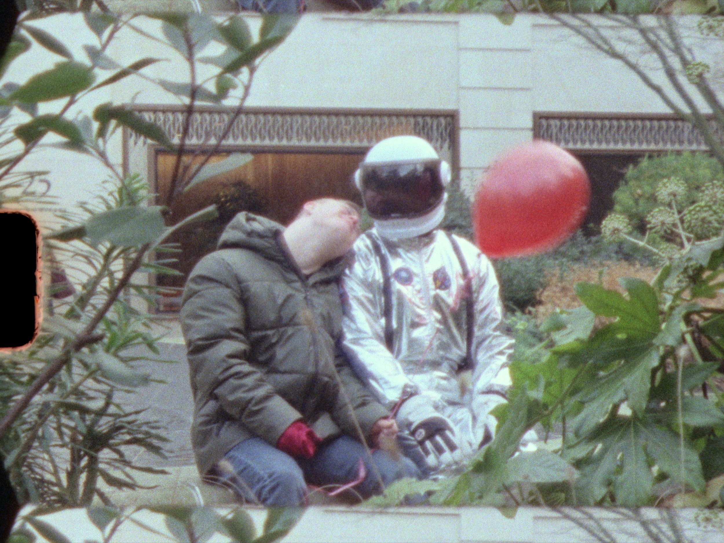 Astronaut and friend sits with red balloon