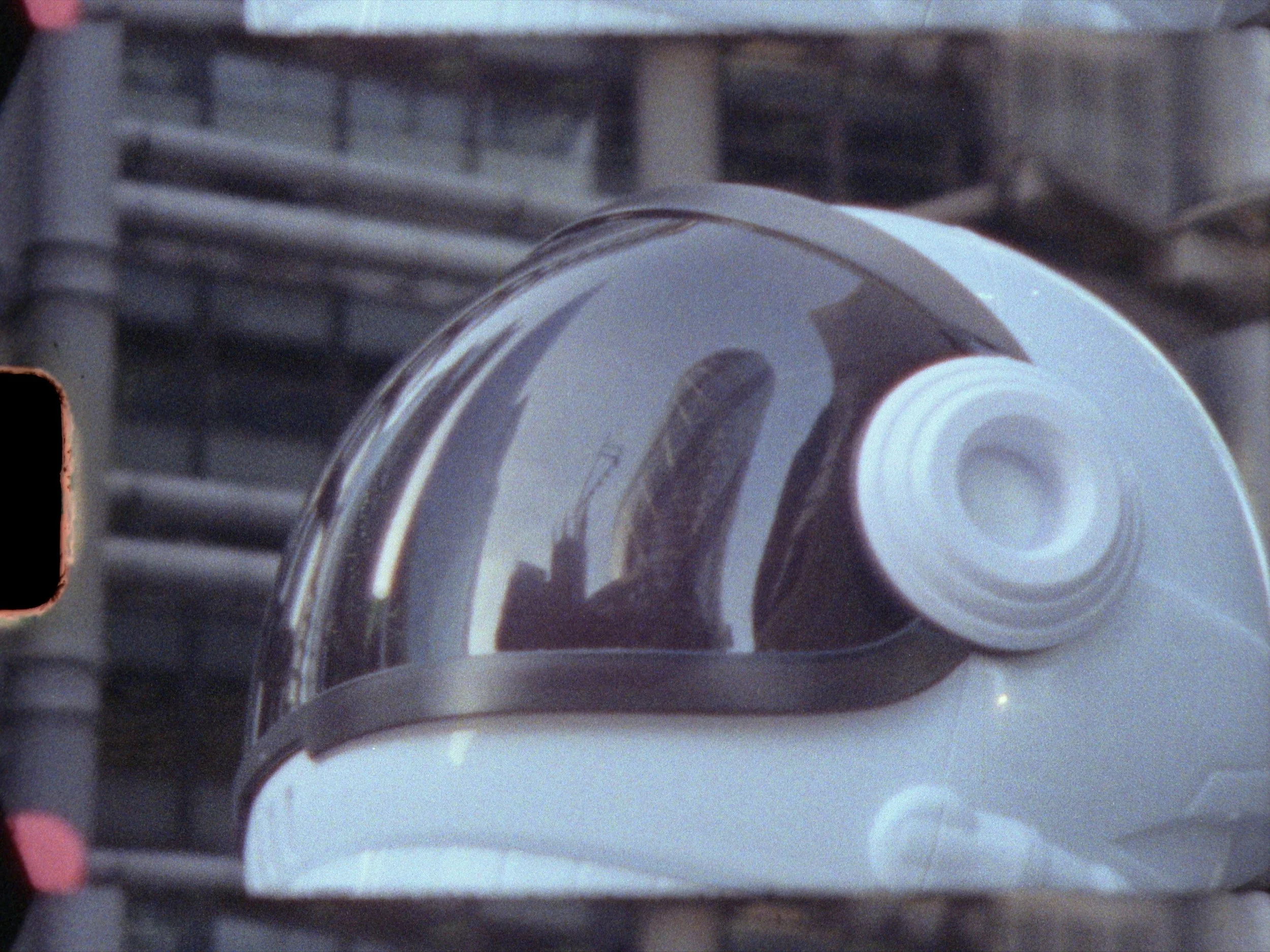 Astronaut looking towards a city skyline in helmet reflection