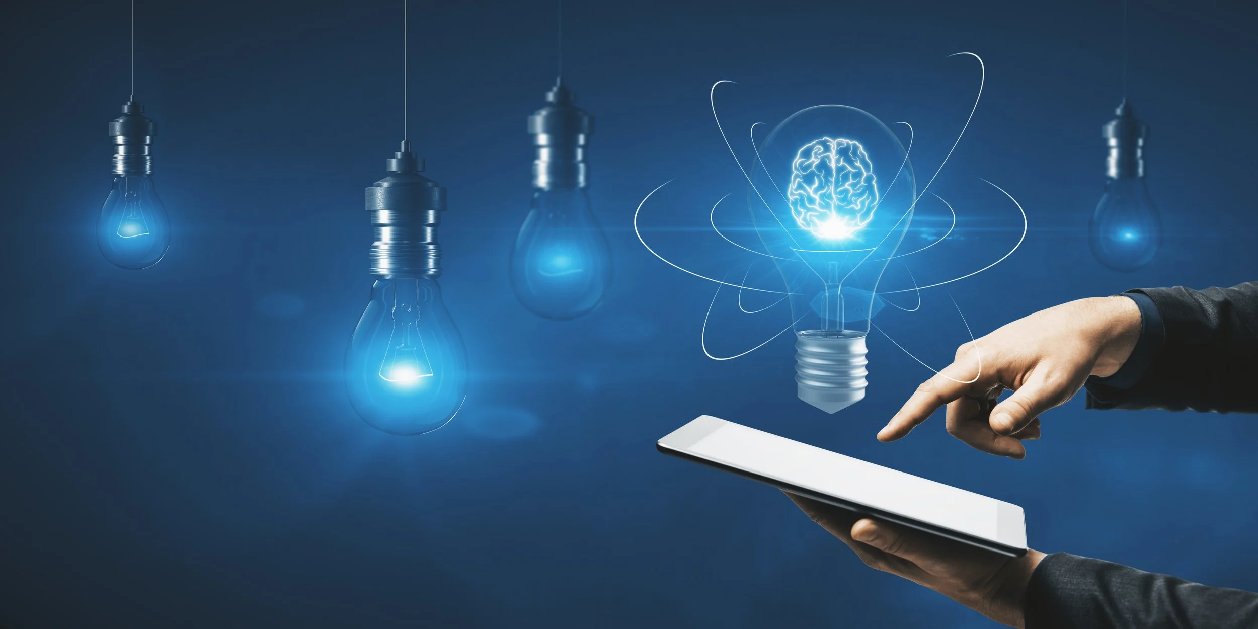 A person holding a tablet with a digital illustration of a floating lightbulb with a glowing brain inside, surrounded by five other hanging lightbulbs, all glowing blue.