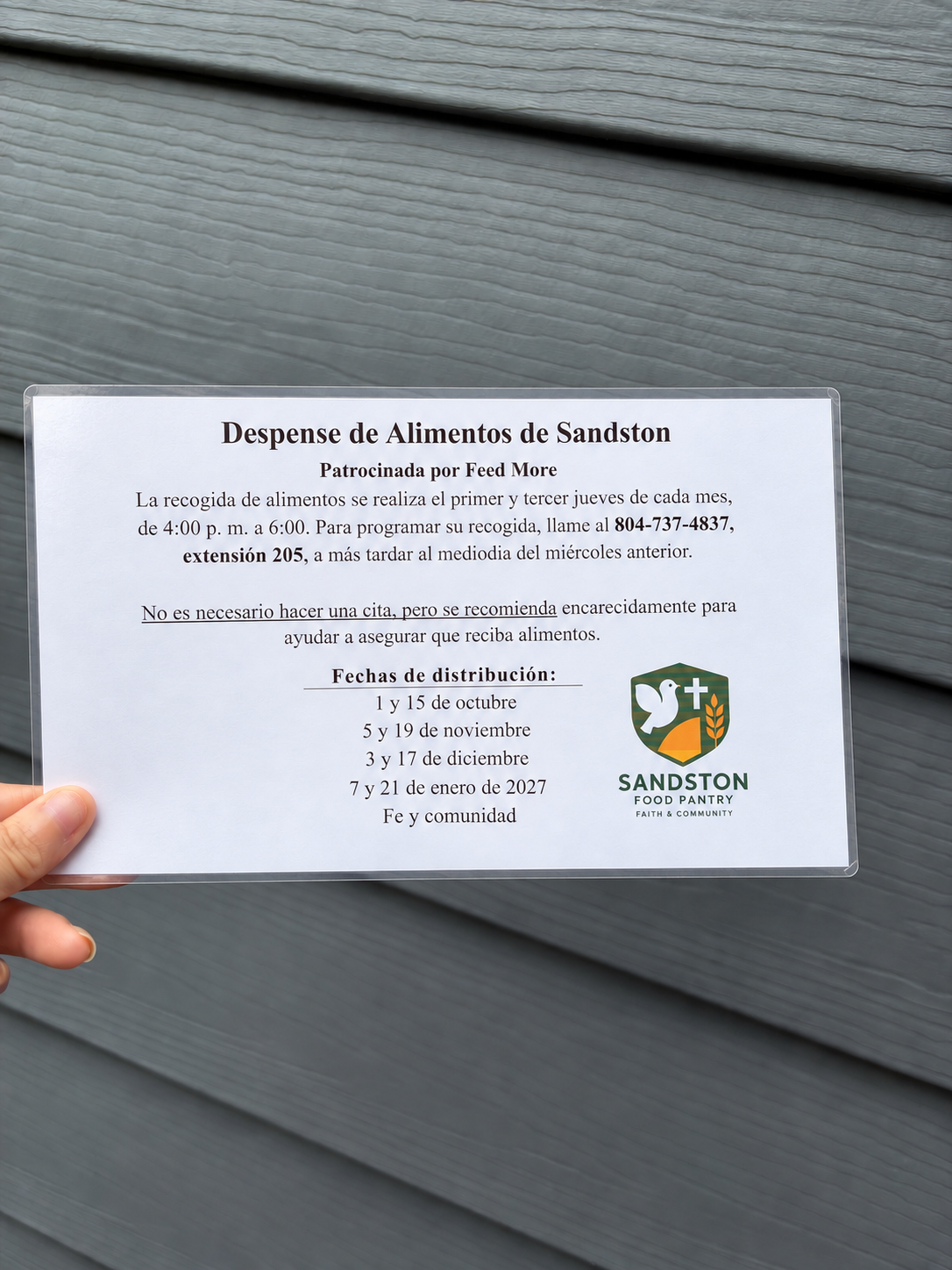 Sign for the Sandstone Food Pantry detailing food donation schedule and contact information, with logo featuring a white dove, a cross, and wheat symbol.