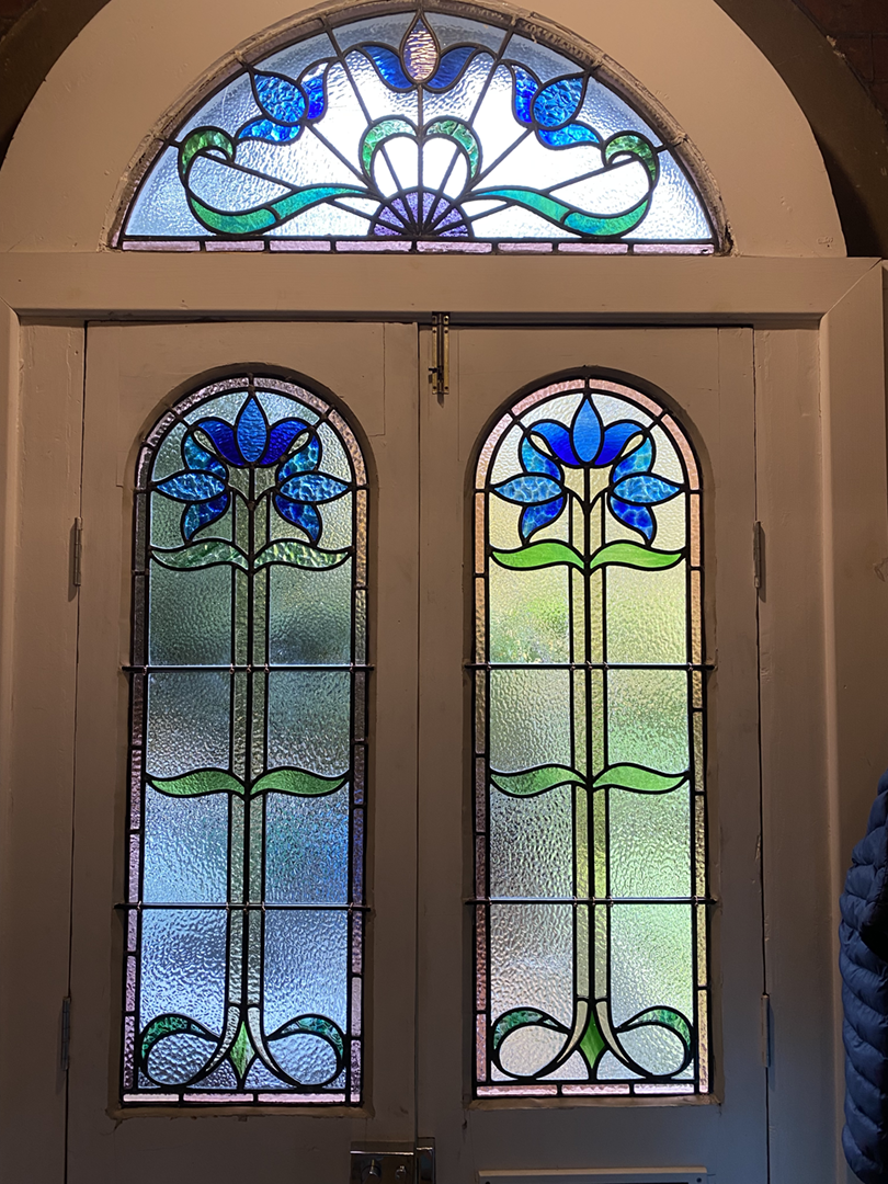 Decorative stained glass windows fully renovated with matching glass in a door and fanlight.