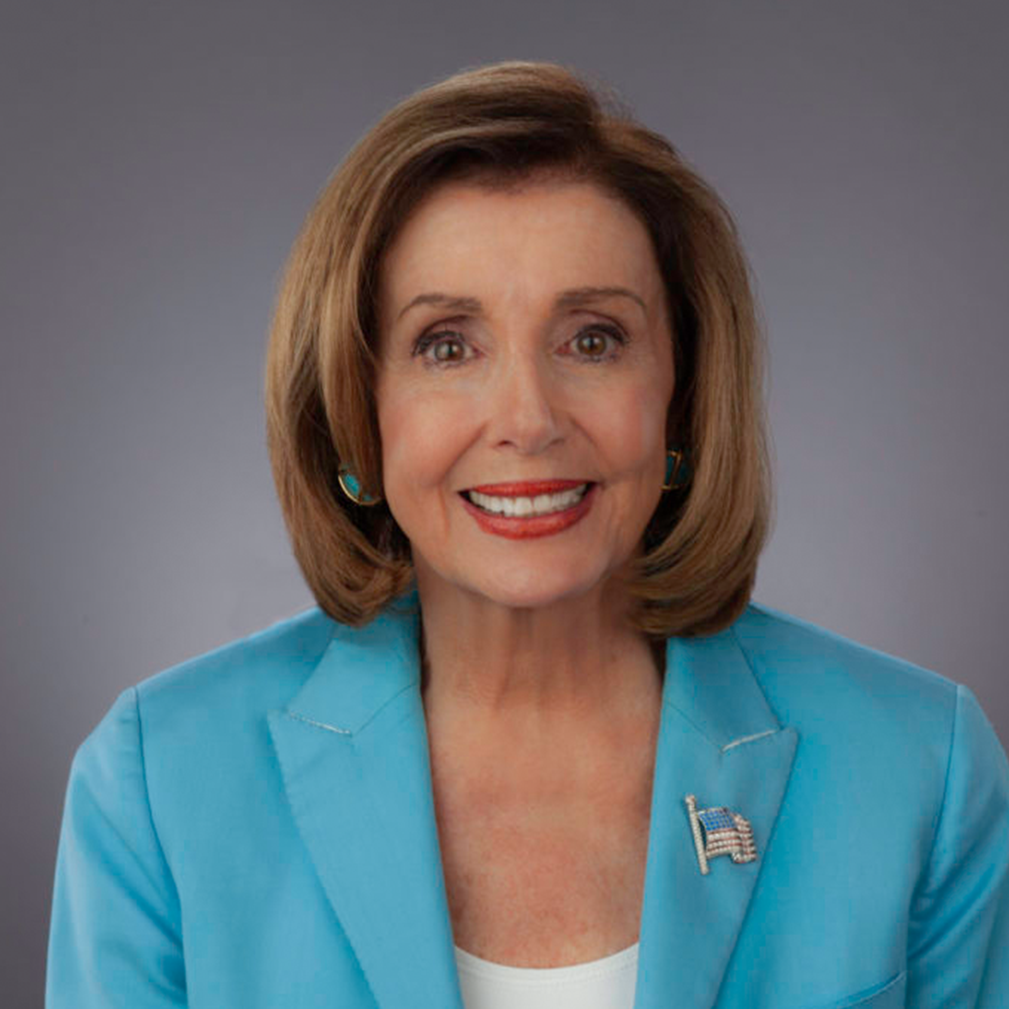 Close-up of a woman with shoulder-length brown hair, wearing a bright blue blazer and a white top, smiling against a gray background.