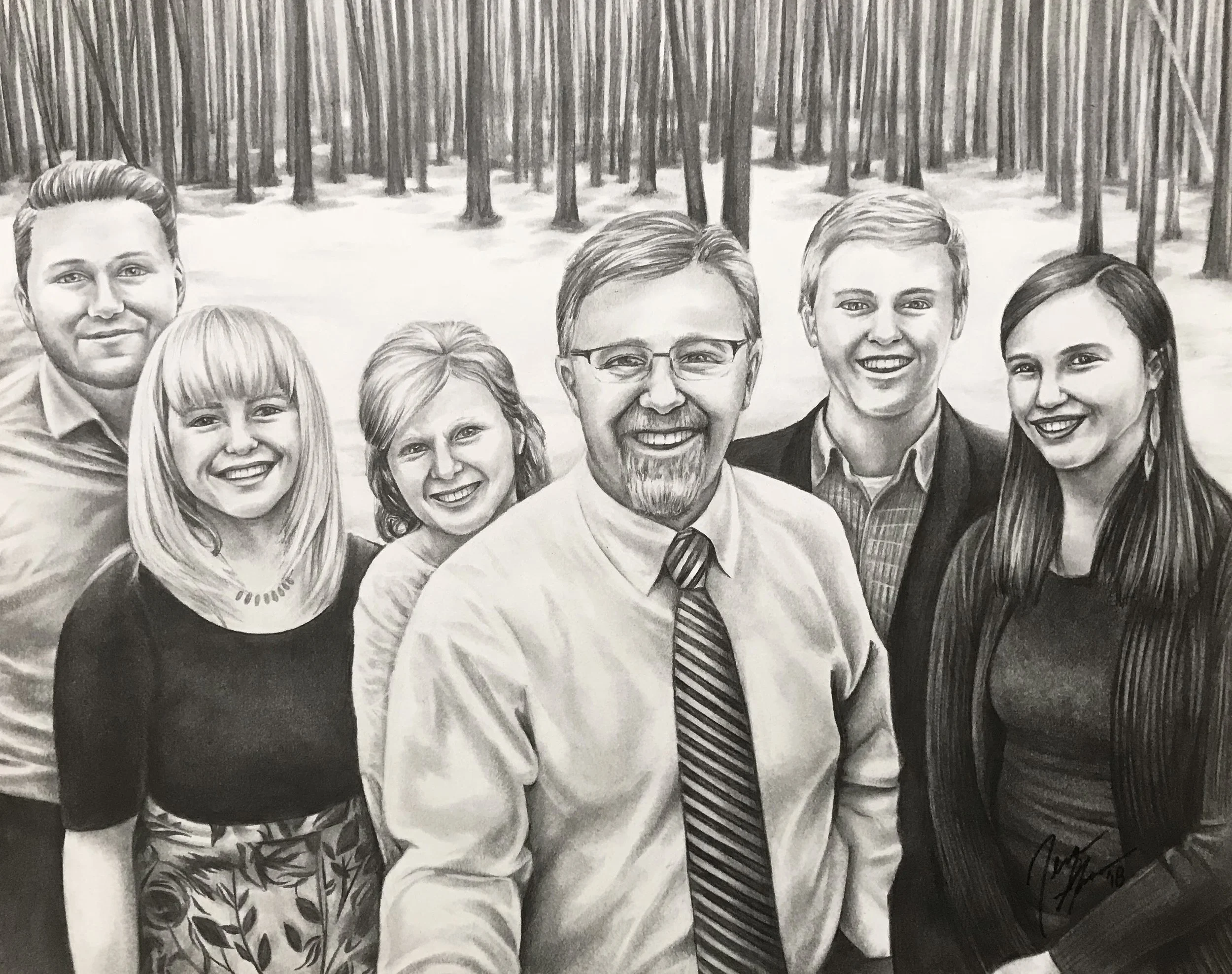 Black and white photo of a group of seven smiling people standing close together outdoors in front of a forest of trees.