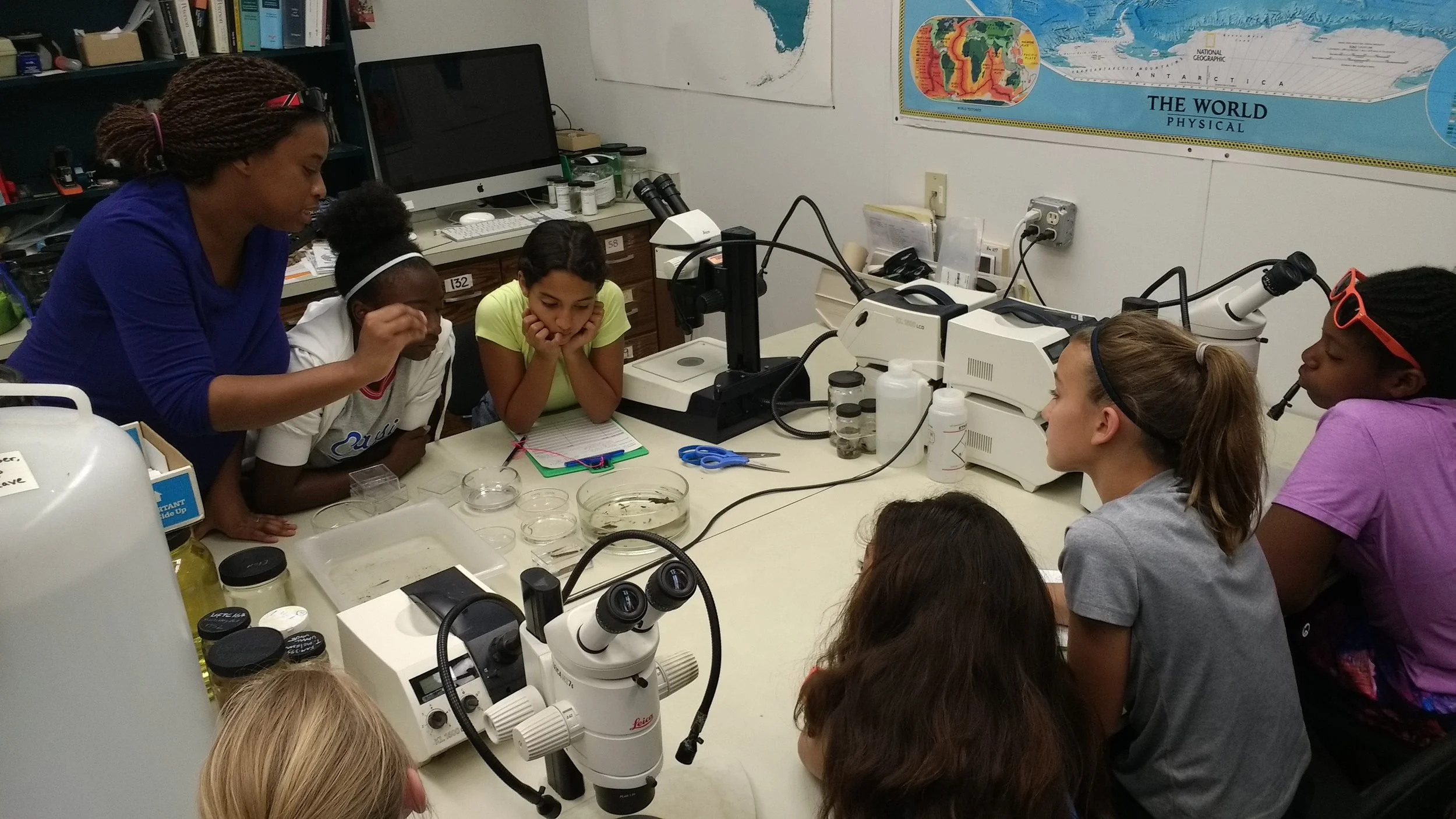 Dr. Adania Flemming working alongside middle school students as they use identification keys, microscopes, and observed characteristics to identify fish and invertebrates collected from a creek during the 2018 UF WiSE Girlz camp.