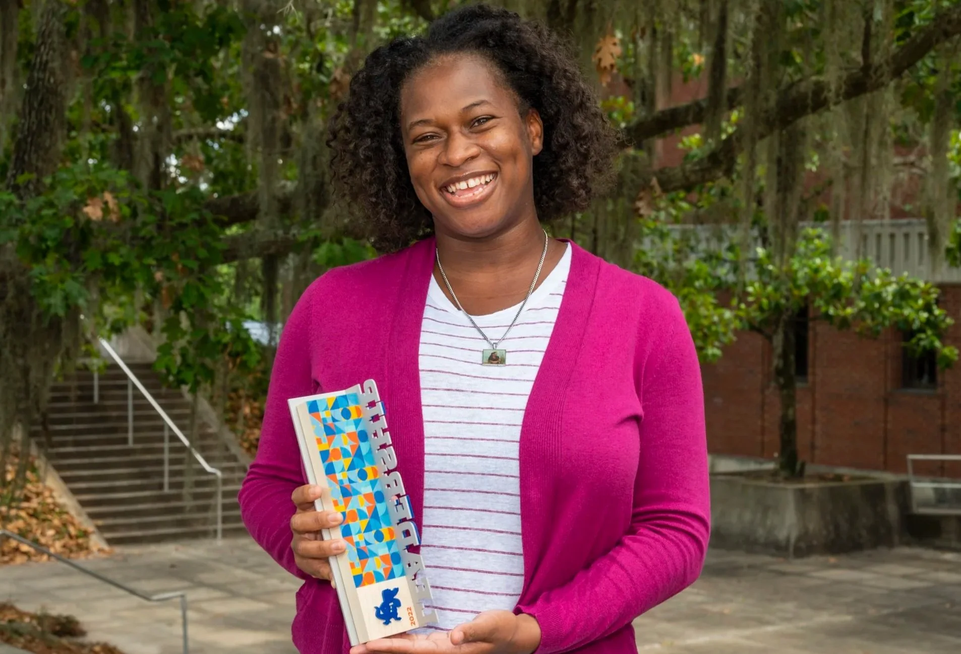 Dr. Adania Flemming holding a University of Florida leadership award recognizing her work advancing diversity, equity, inclusion, and community in STEM.